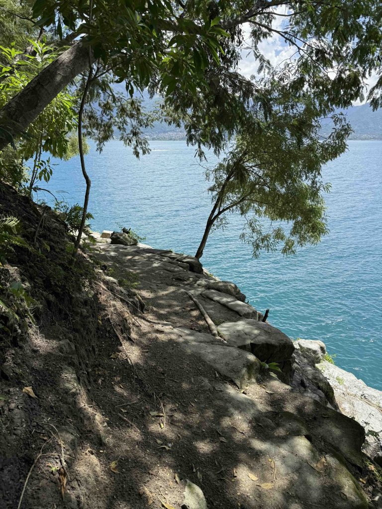 Shaded dirt path along the cliffside above turquoise water at Cerro Tzank’ujil in San Marcos