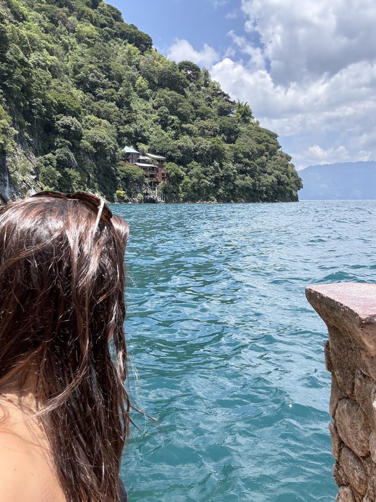 Woman on boat looking at turquoise water and cliffside homes on Lake Atitlán