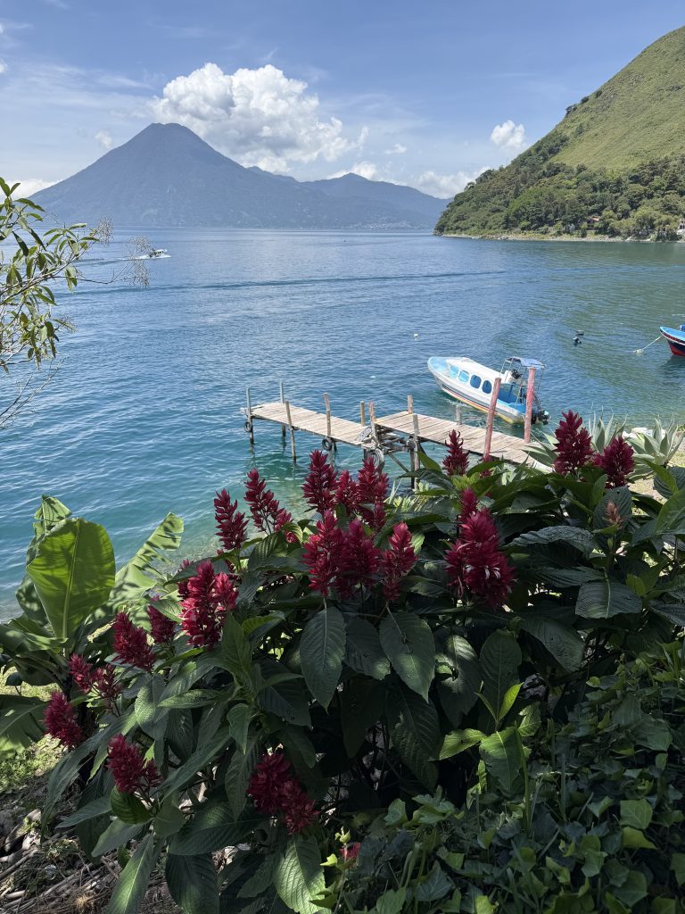 Small dock and boats on turquoise Lake Atitlán with volcano in distance