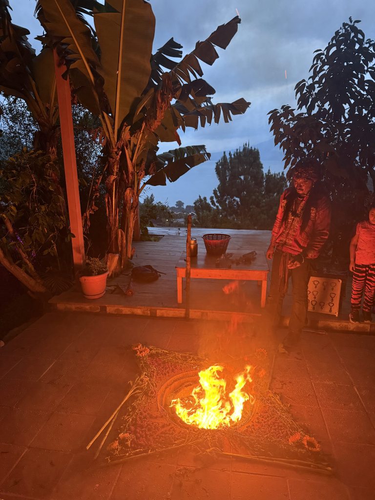 Traditional Mayan fire ceremony at night with guide standing beside the flames at Lake Atitlán