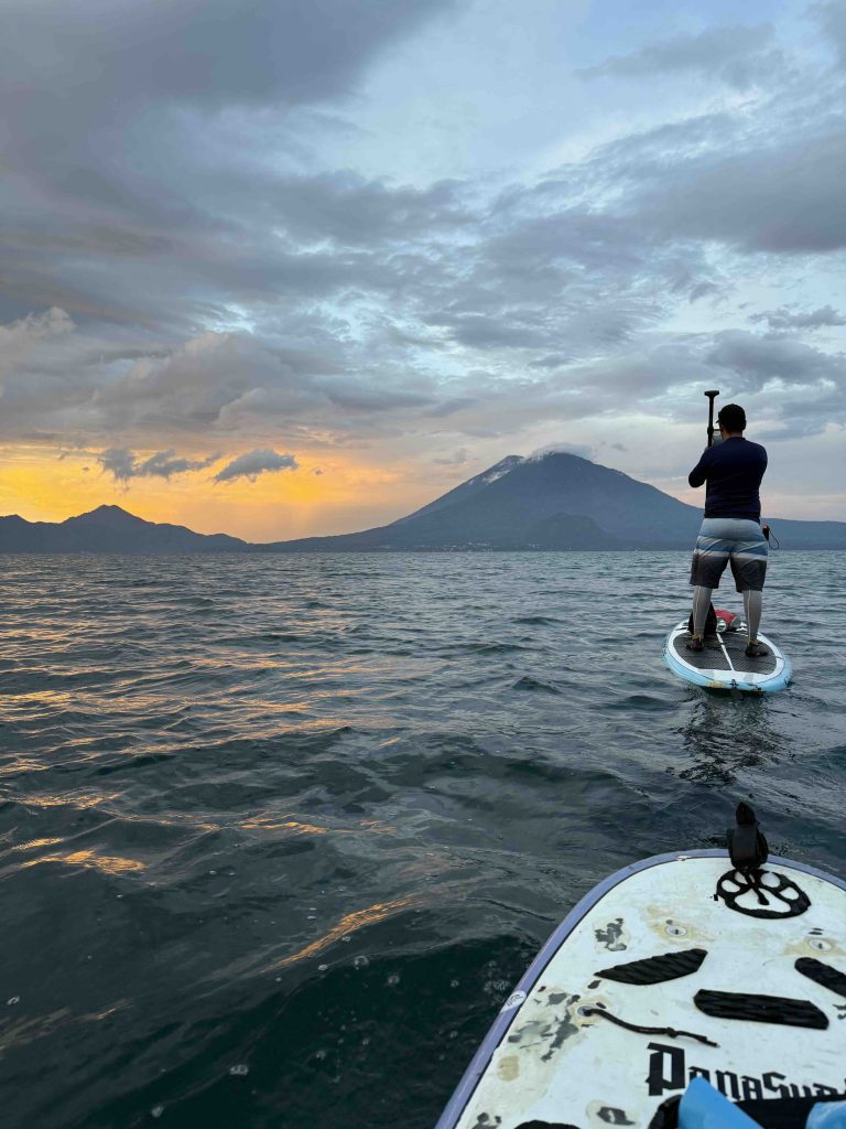 Paddle boarder facing San Pedro volcano during a sunrise tour on Lake Atitlán