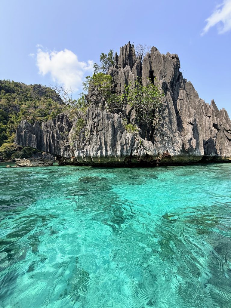 Dramatic limestone cliffs rising above clear turquoise water at Twin Lagoon in Coron, Philippines.