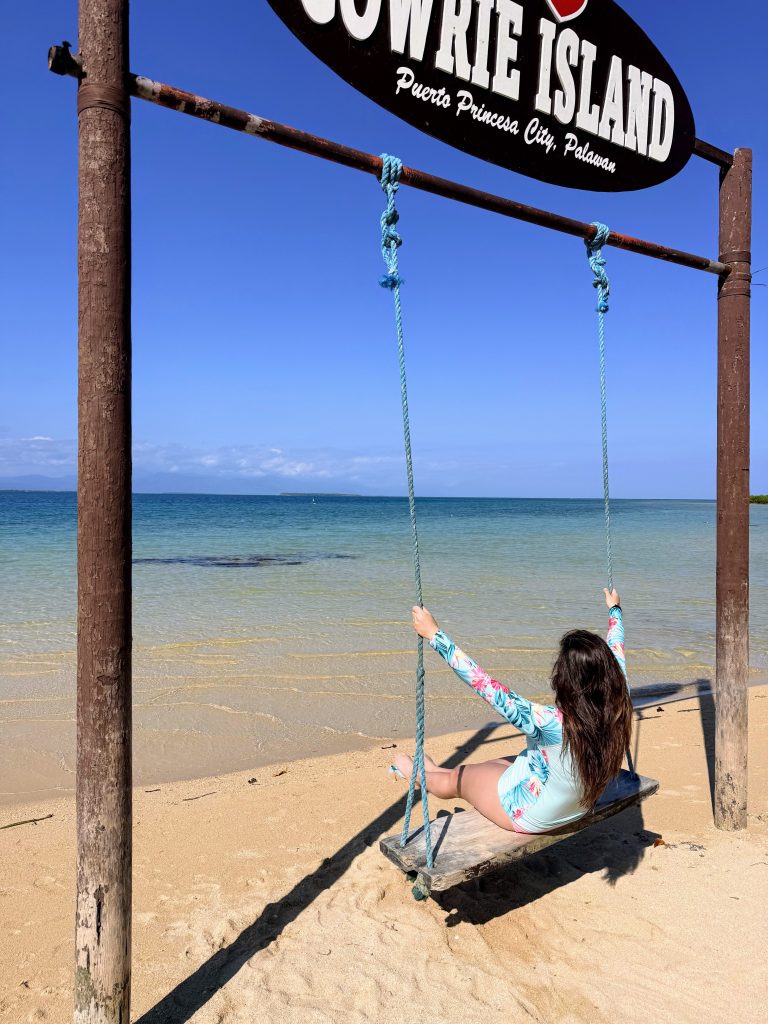 Traveler on a beach swing at Cowrie Island during Honda Bay island hopping in Puerto Princesa, Philippines.