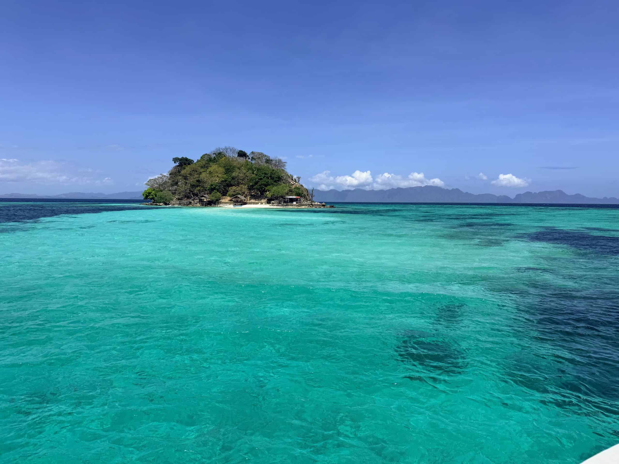 Small tropical island surrounded by clear turquoise water on the Sea Expedition from El Nido to Coron, Philippines.