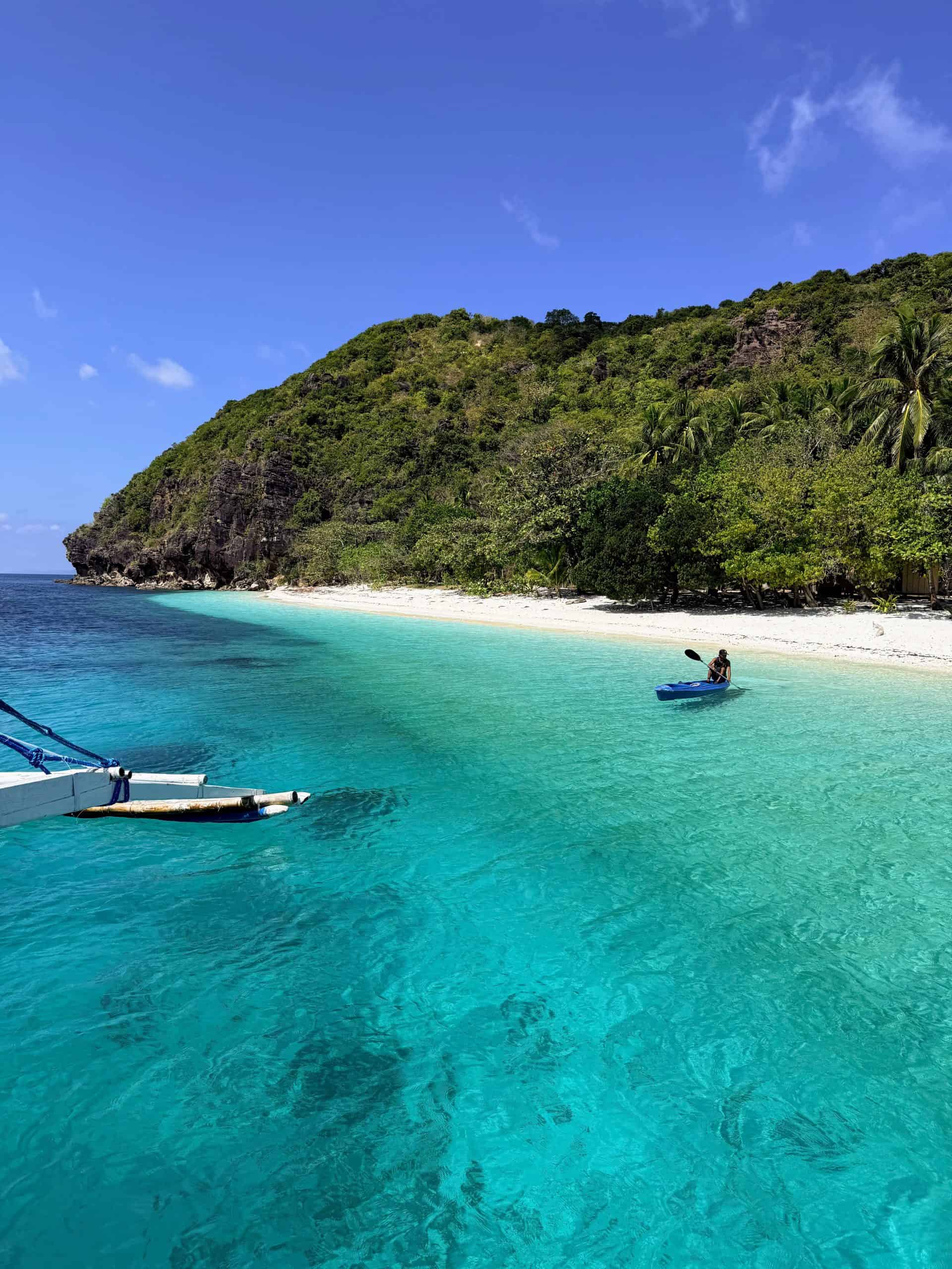 Turquoise cove and white-sand shoreline seen from the Sea Nomads boat during the El Nido to Coron expedition in the Philippines.