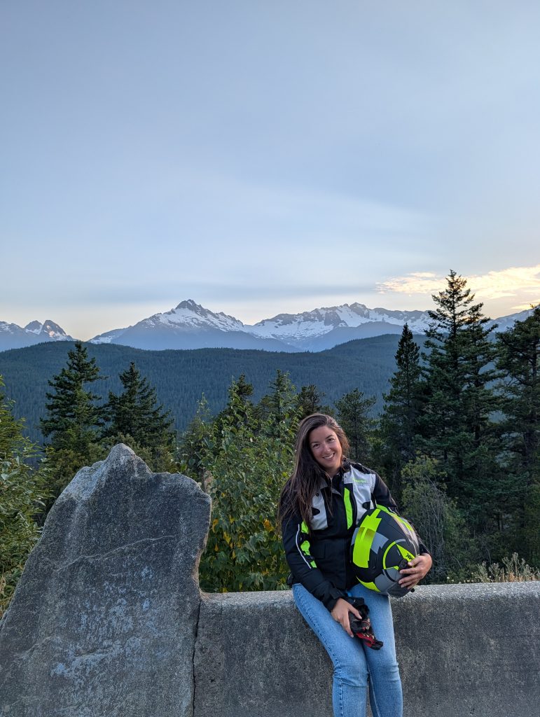 Traveler holding a motorcycle helmet with the Tantalus mountain view at sunset along the Sea to Sky Highway