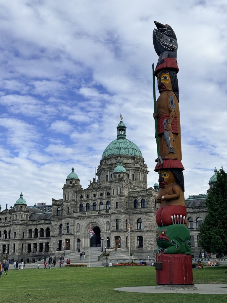 Totem pole standing in front of the British Columbia Parliament Buildings in Victoria.