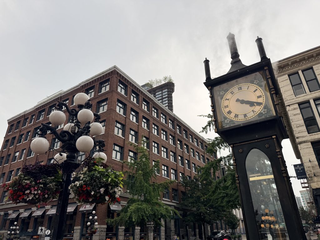 Gastown Steam Clock surrounded by historic brick buildings and flower baskets in downtown Vancouver.