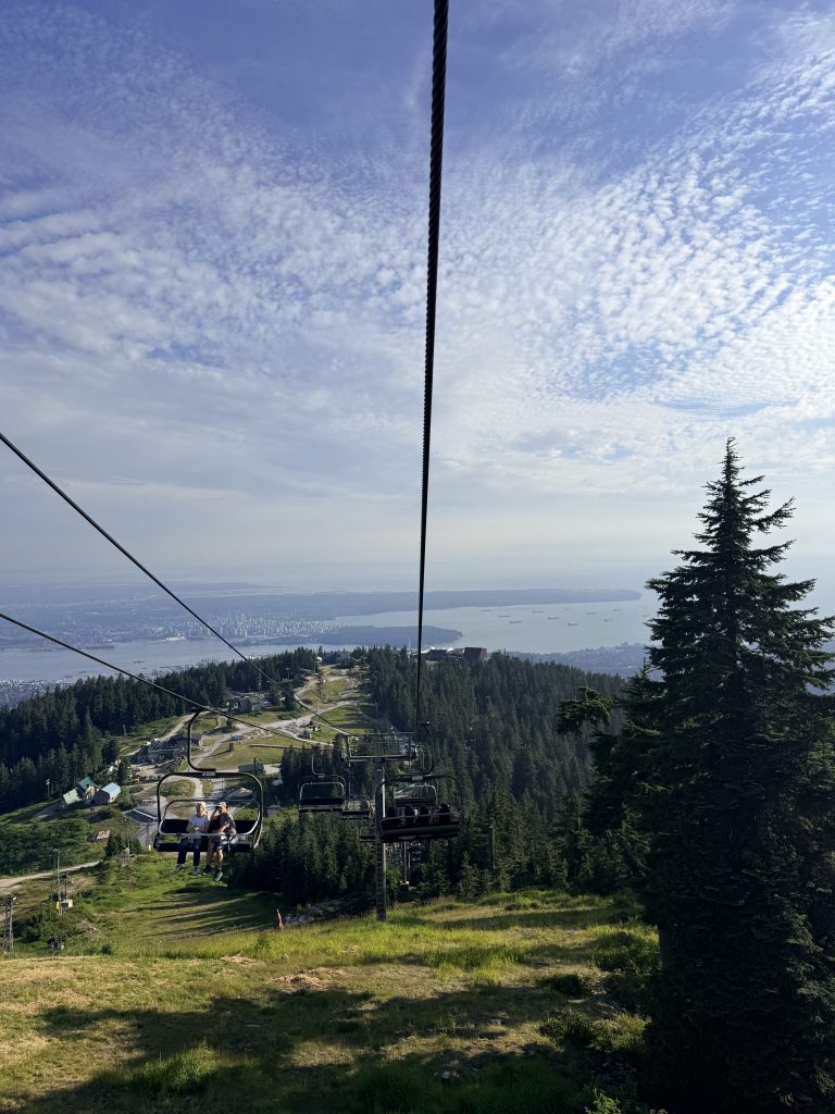 Chairlift descending Grouse Mountain with sweeping views over Vancouver and the coastline.