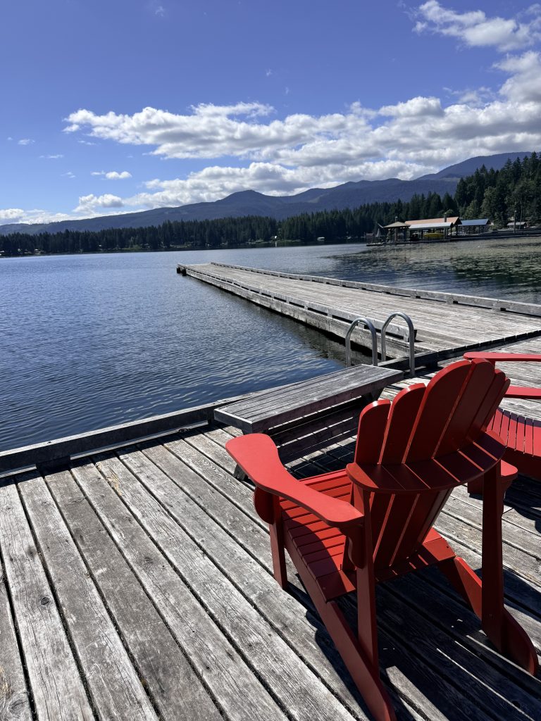 Red Adirondack chairs overlooking a dock and mountain scenery at Sproat Lake on Vancouver Island.