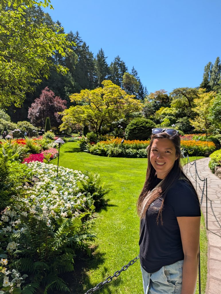 Annie standing beside colourful summer flower beds in the Sunken Garden at Butchart Gardens.