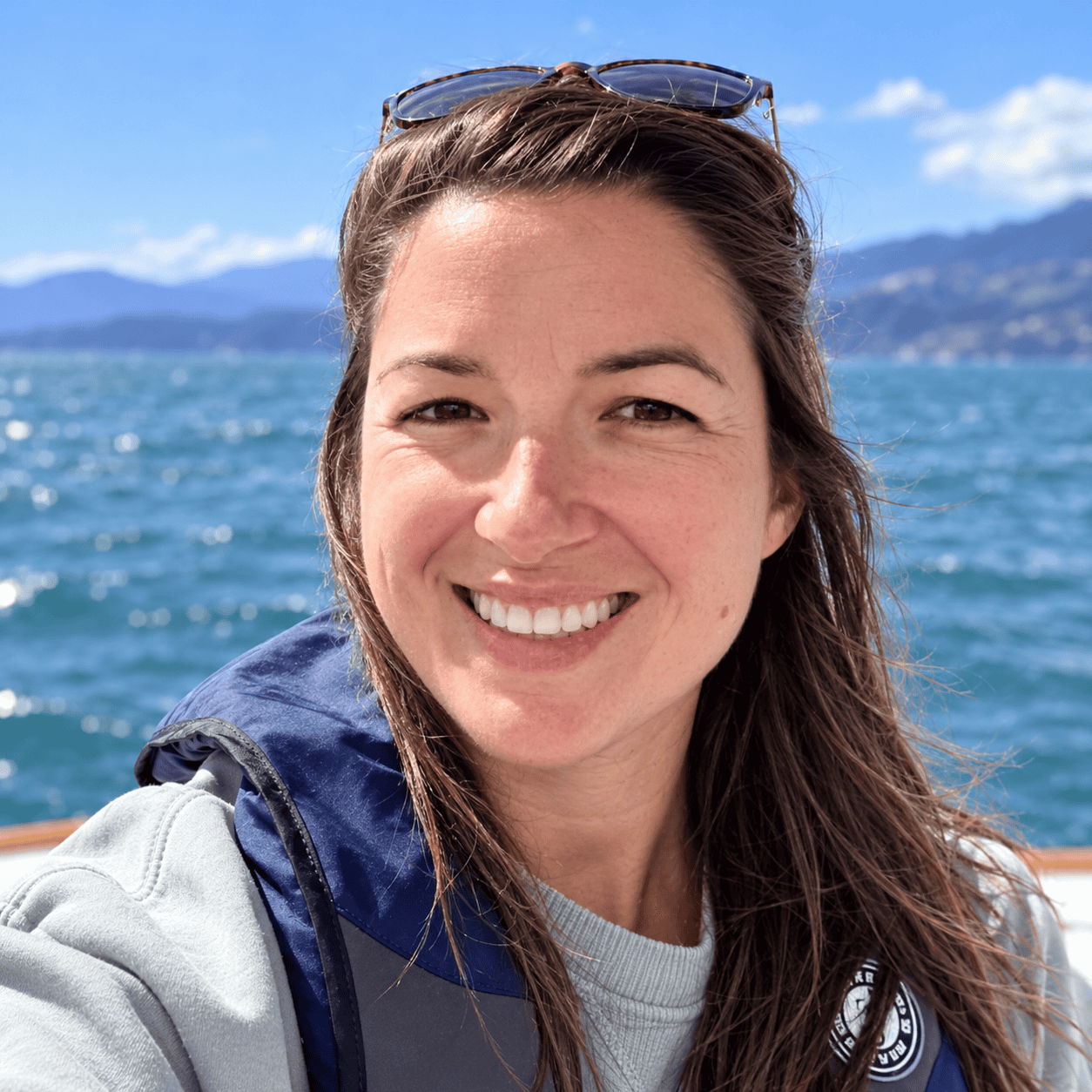 Annie smiling by the water with mountains in the background