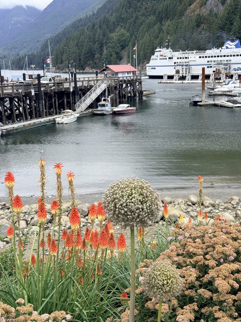 BC Ferries vessel at Horseshoe Bay terminal behind colourful waterfront flowers.