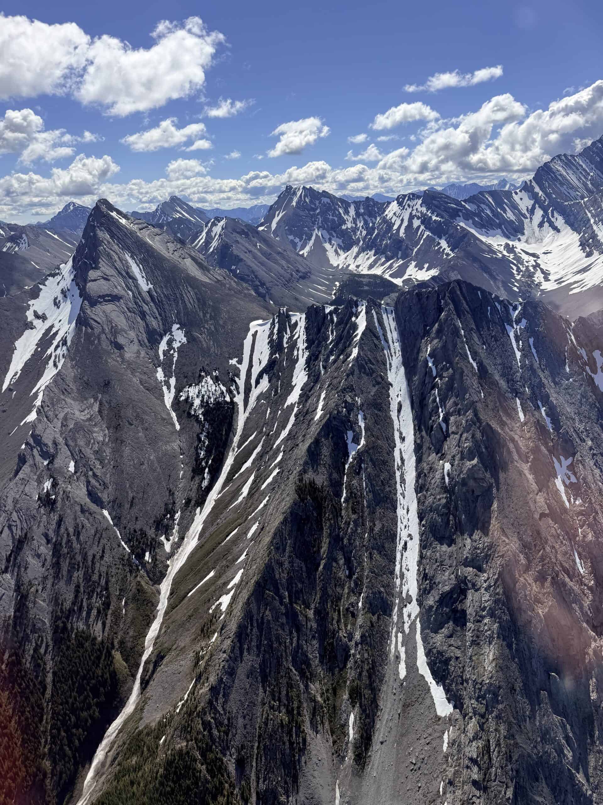 Jagged mountain peaks with streaks of snow viewed from a helicopter near Canmore.