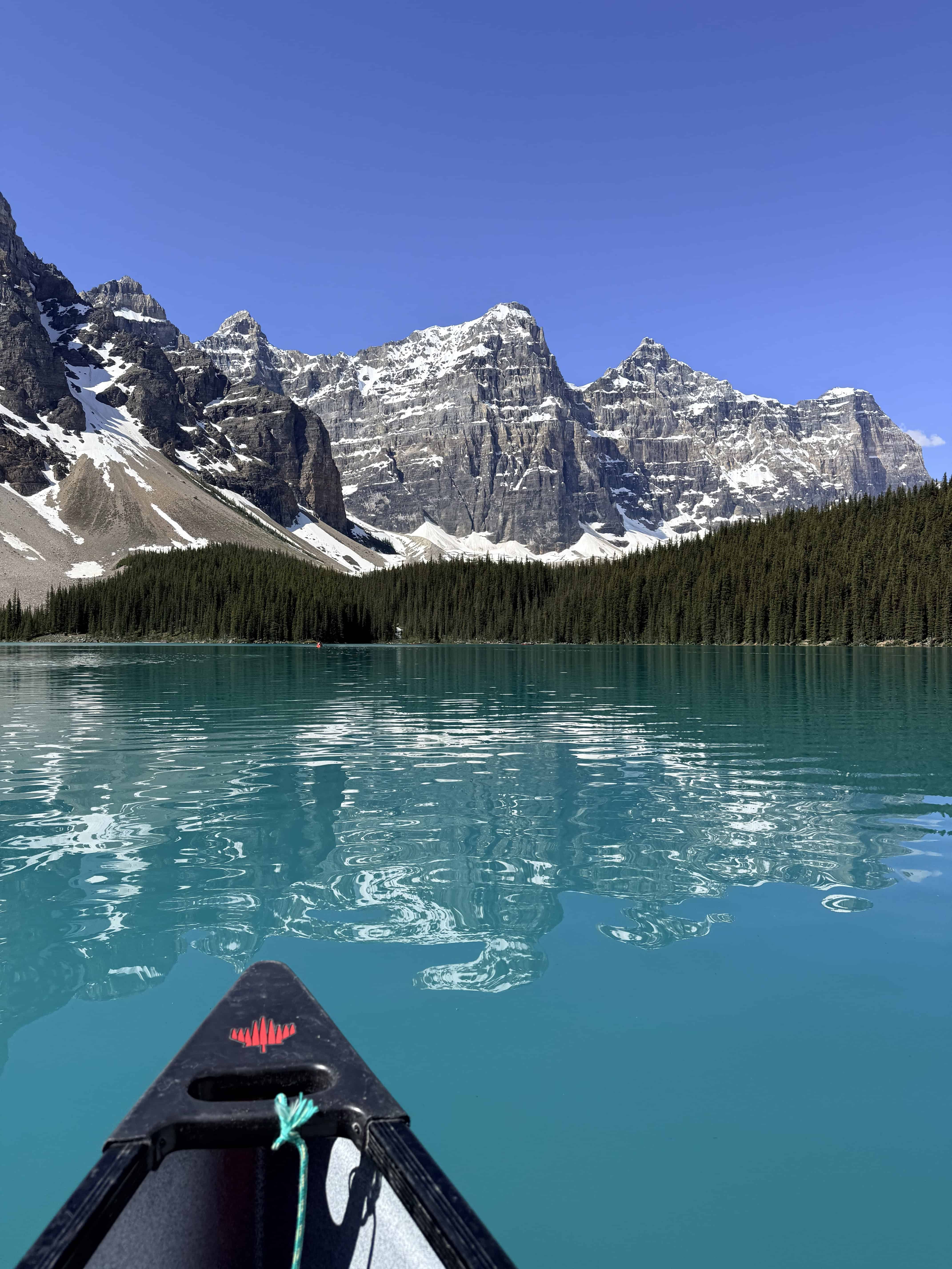 Canoe bow pointing across Moraine Lake toward the dramatic Valley of the Ten Peaks in Banff National Park.
