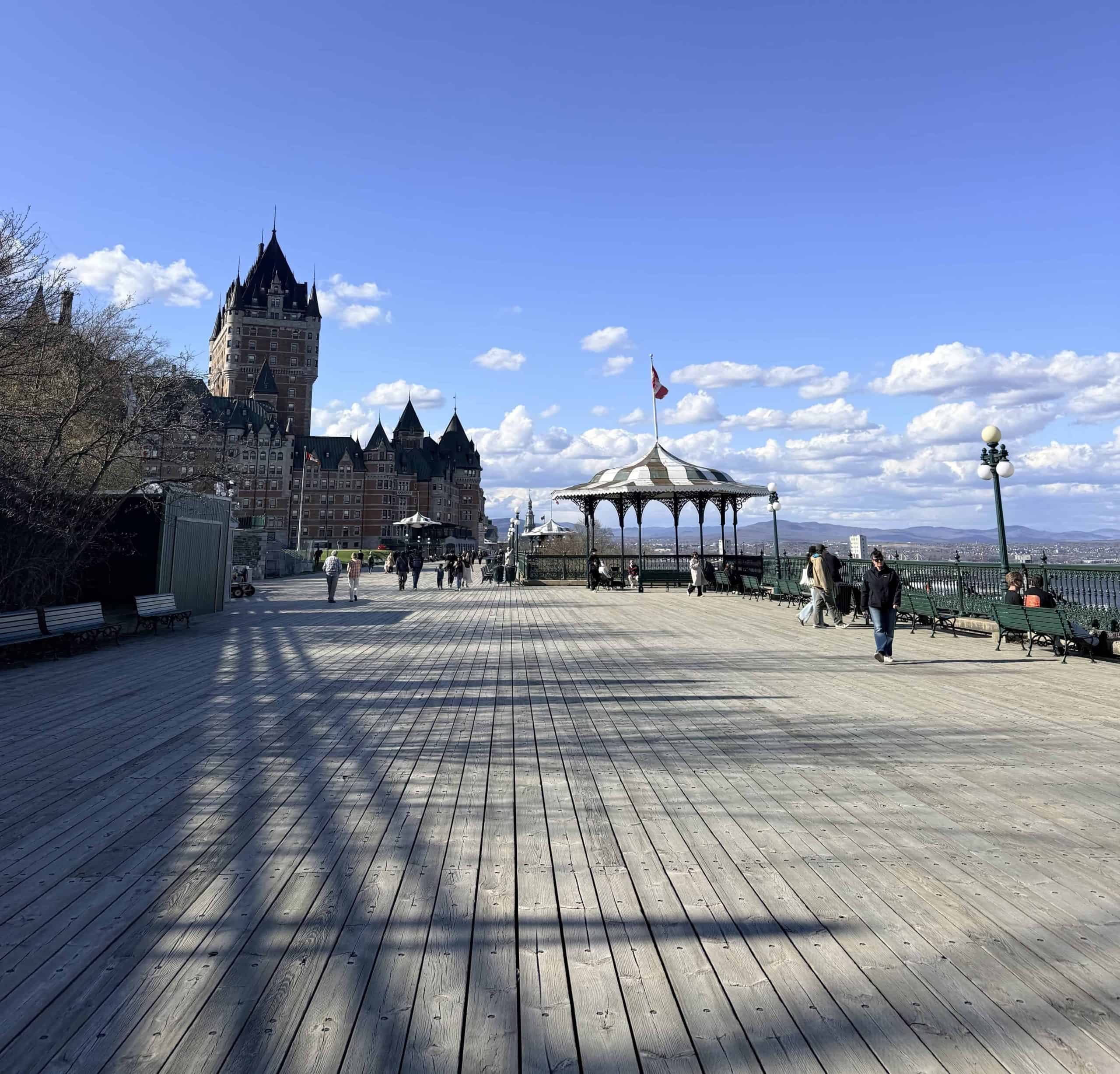 Château Frontenac and the gazebo along Dufferin Terrace in Quebec City under a bright blue sky.