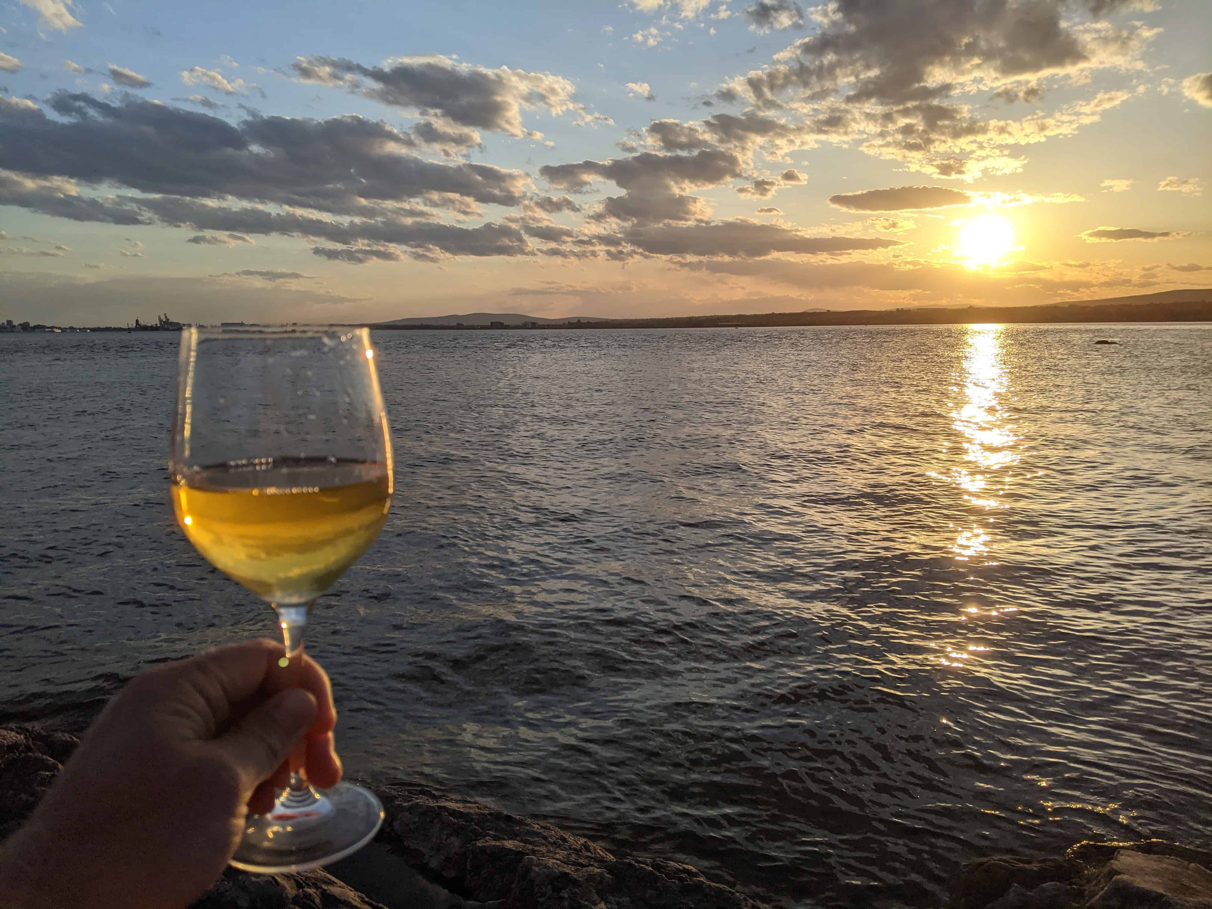 Glass of white wine at sunset overlooking the St. Lawrence River from Île d’Orléans, Quebec.