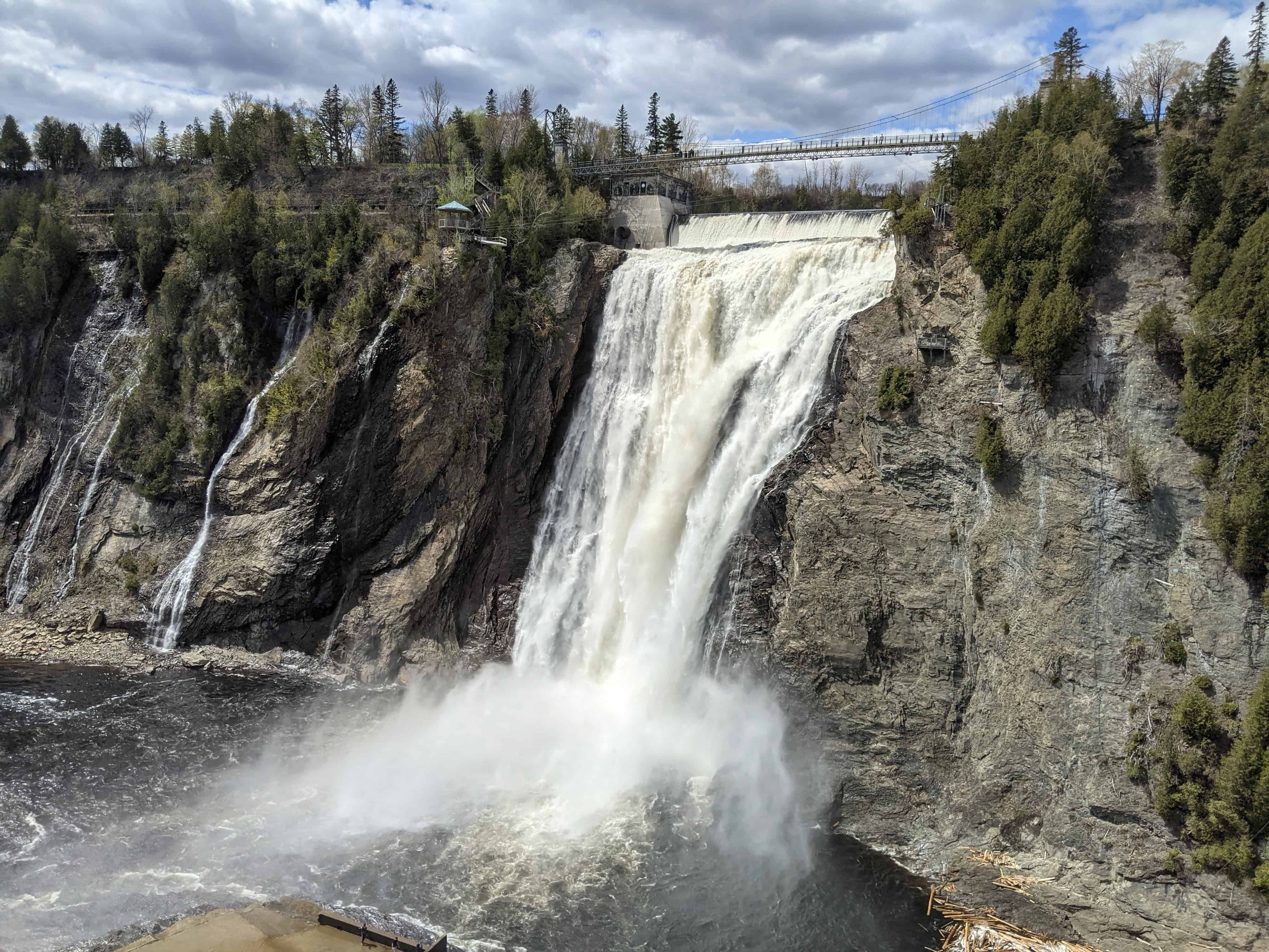 Montmorency Falls cascading over the cliffs near Quebec City, with the suspension bridge visible above the waterfall.