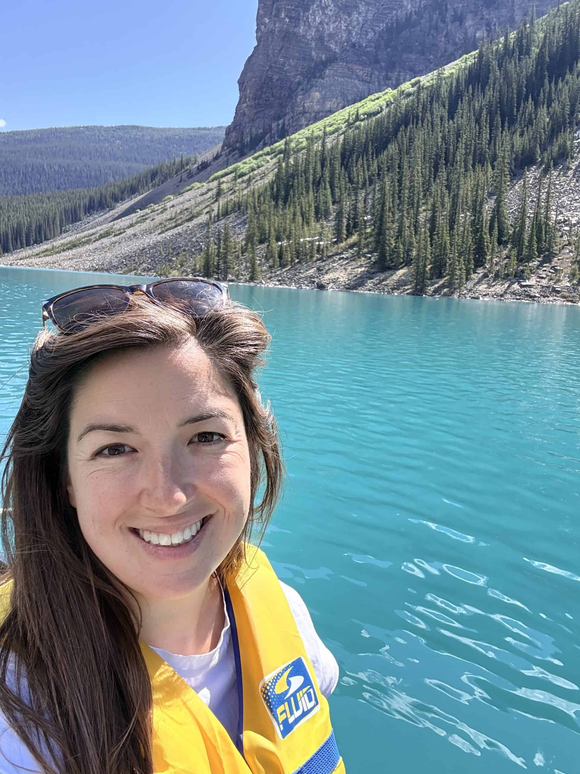 Smiling woman wearing a life jacket while canoeing on the turquoise water of Moraine Lake in Banff National Park