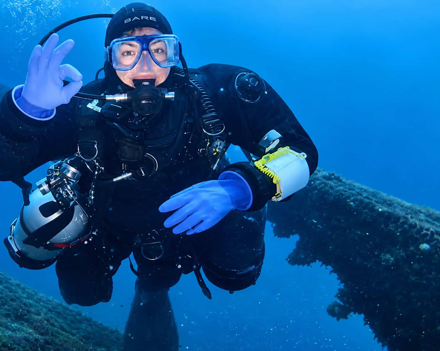 Technical scuba diver giving the OK signal underwater above a coral reef