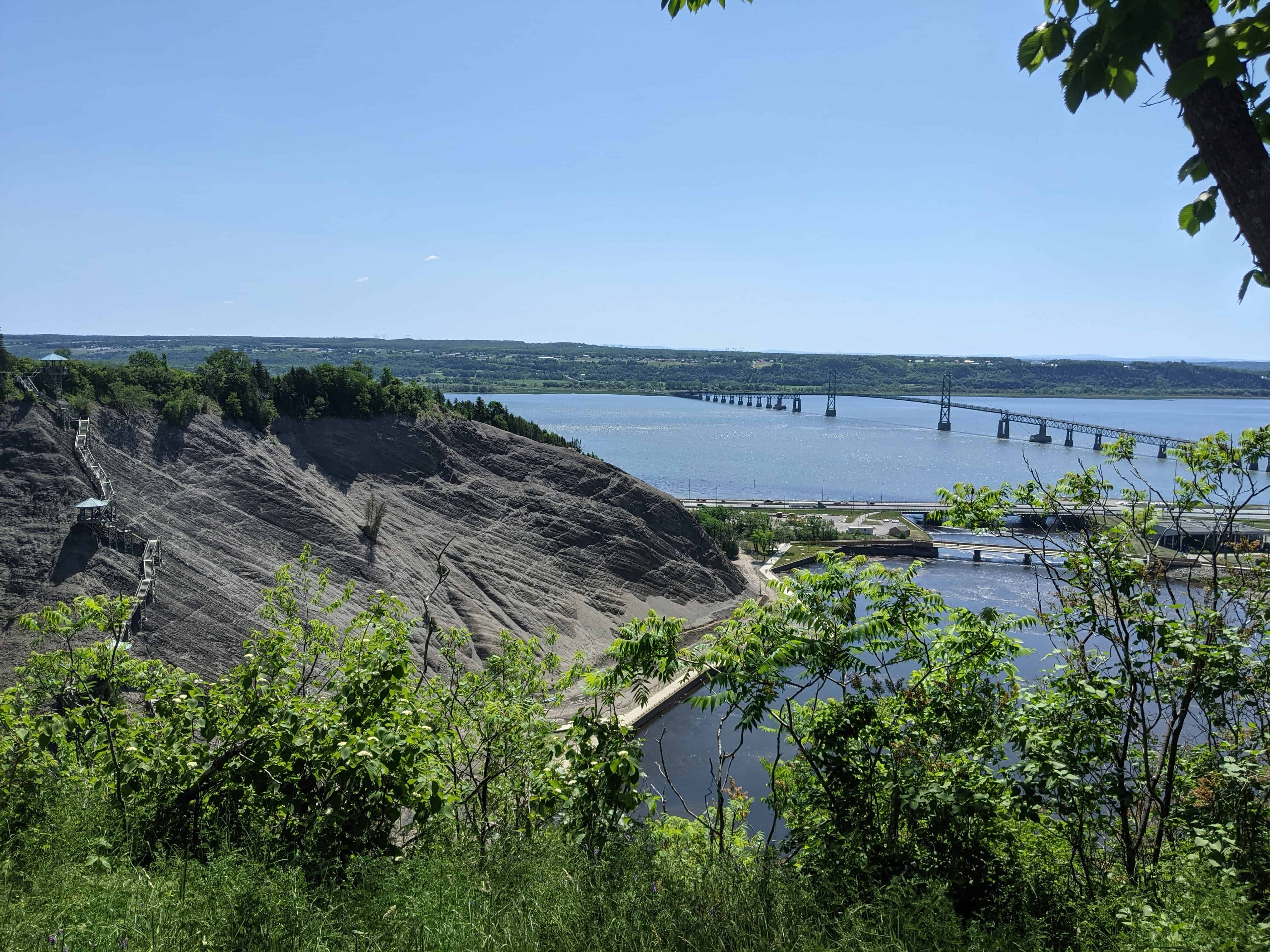 View from Montmorency Falls toward Île d’Orléans across the St. Lawrence River, with the bridge and shoreline in the distance.