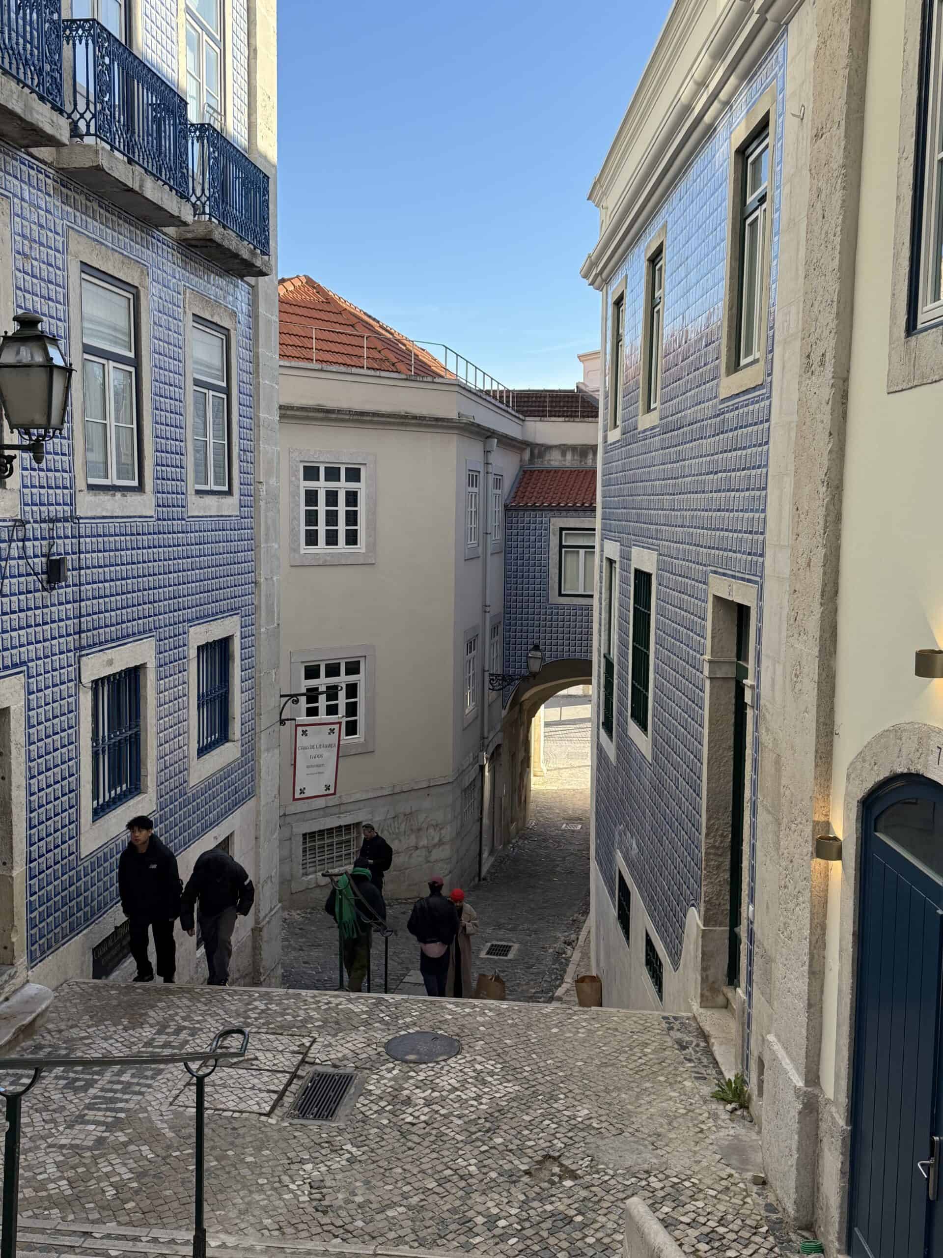 Narrow stairway between historic buildings decorated with blue azulejo tiles in Alfama, Lisbon.