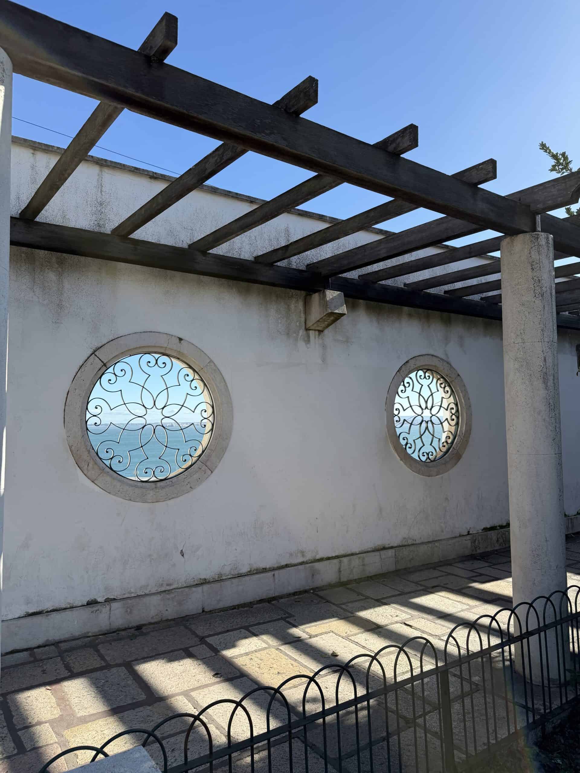 Wooden pergola and decorative circular ironwork windows at Miradouro de Santa Luzia in Alfama, Lisbon.