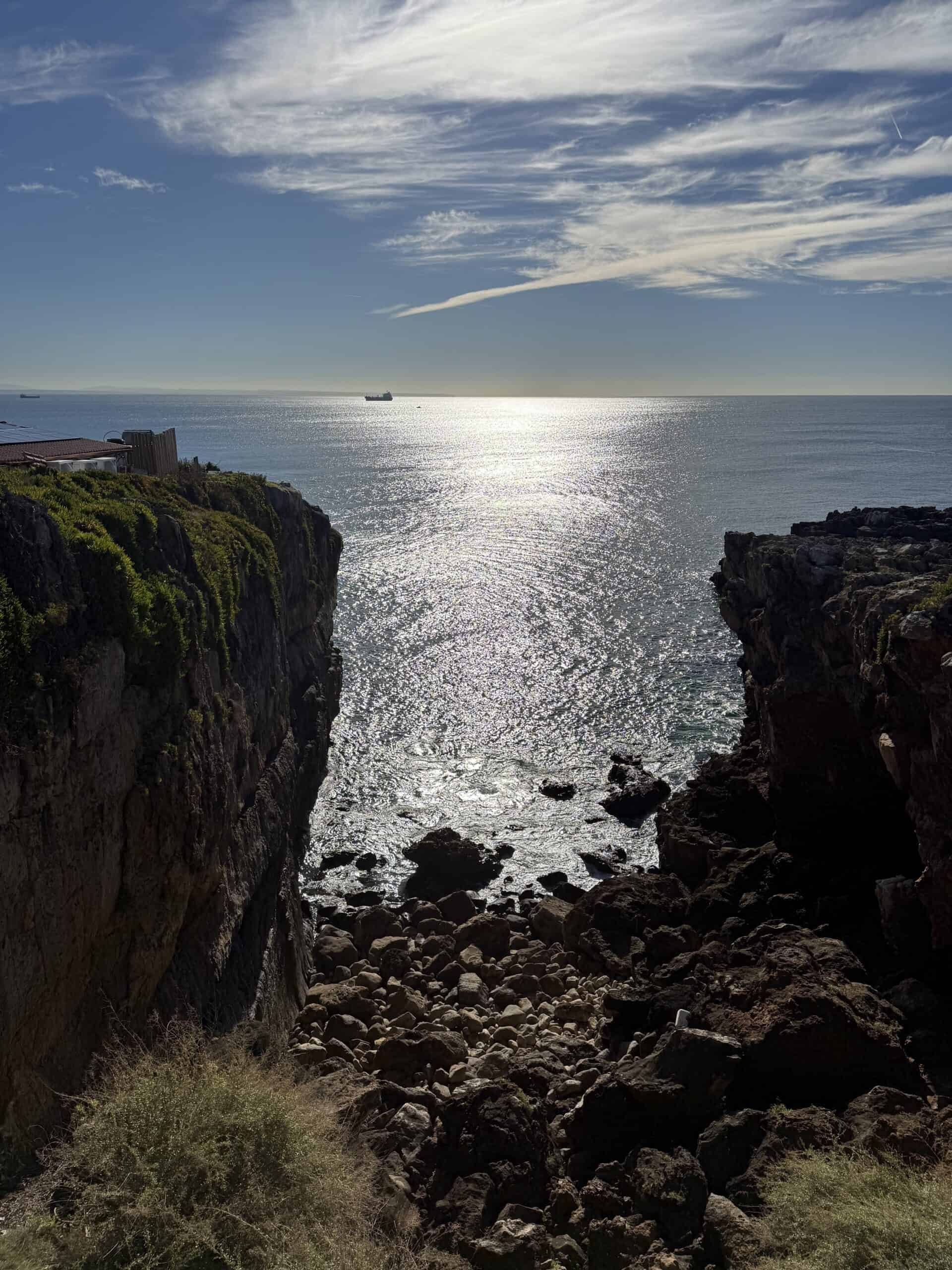 Sunlight sparkling on the Atlantic between steep cliffs at Boca do Inferno in Cascais.