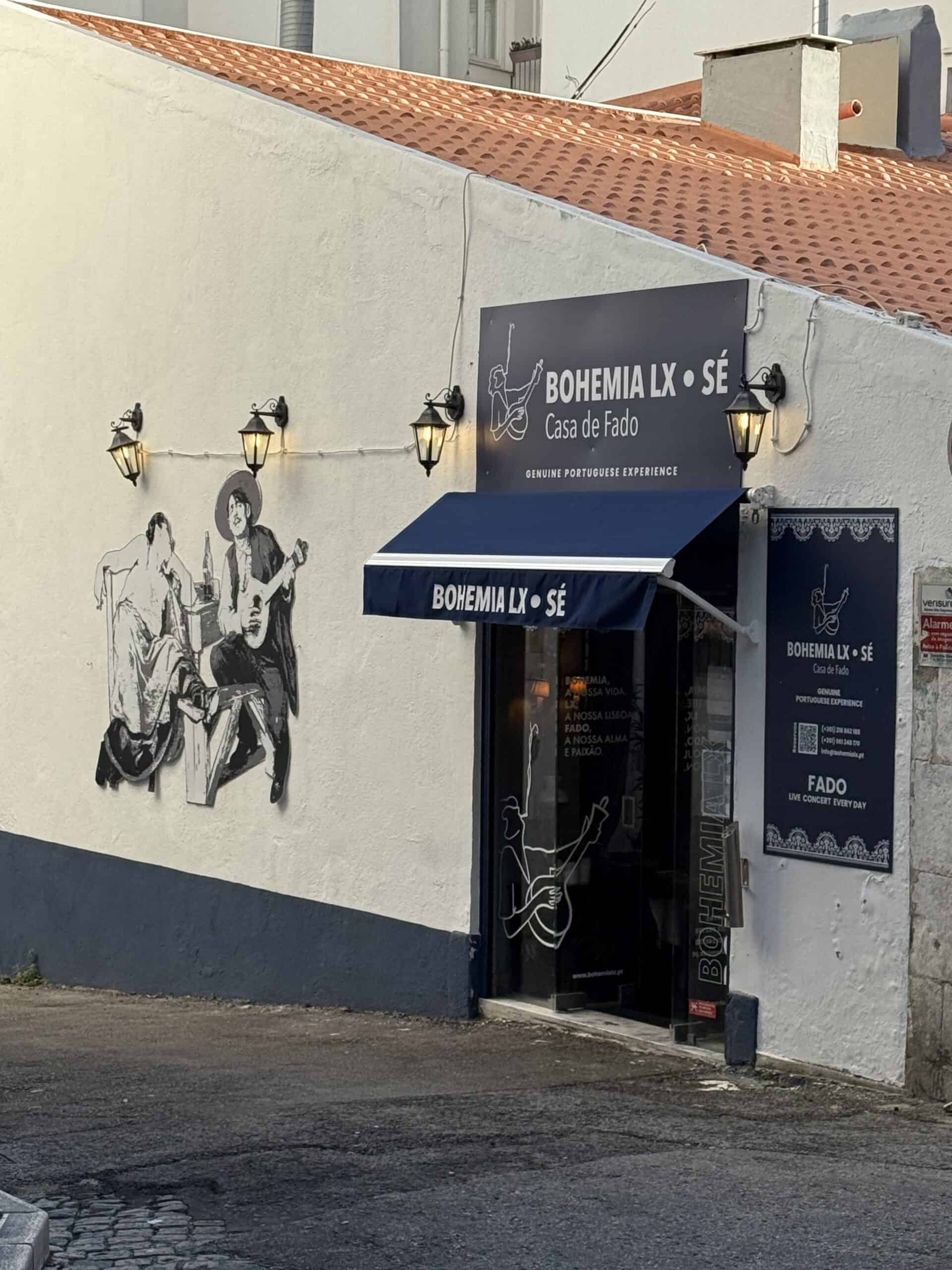Exterior of Bohemia LX Sé fado restaurant in Lisbon, featuring a black-and-white mural of Portuguese musicians, traditional lanterns and a dark blue entrance.