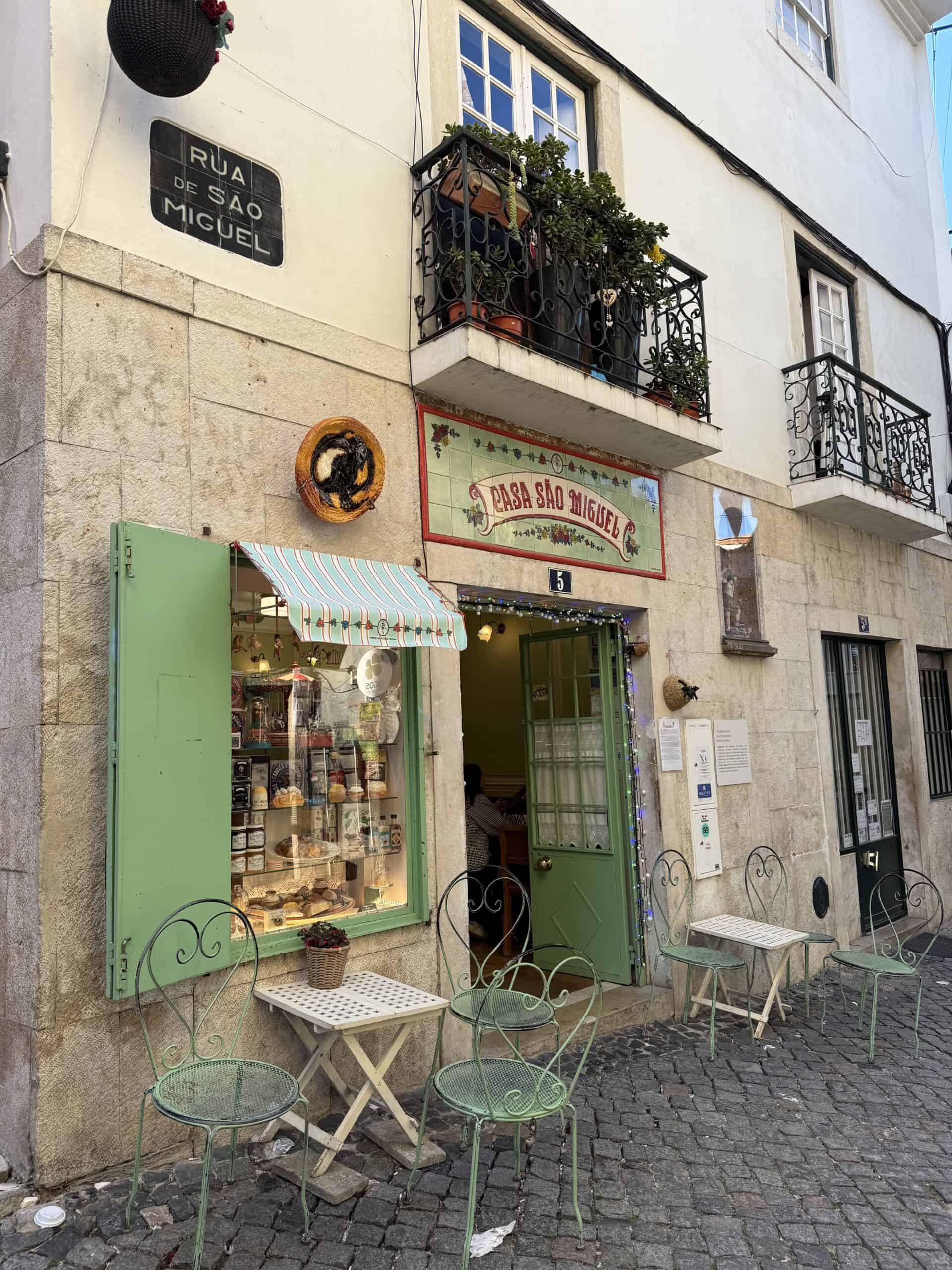 Casa São Miguel café in Alfama with green shutters and outdoor tables.