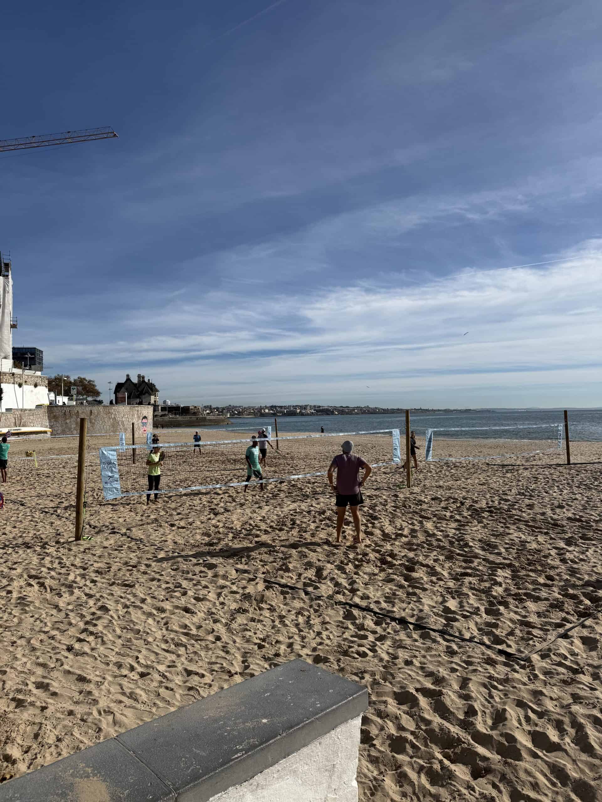 People playing beach volleyball on the sandy coastline of Cascais, Portugal