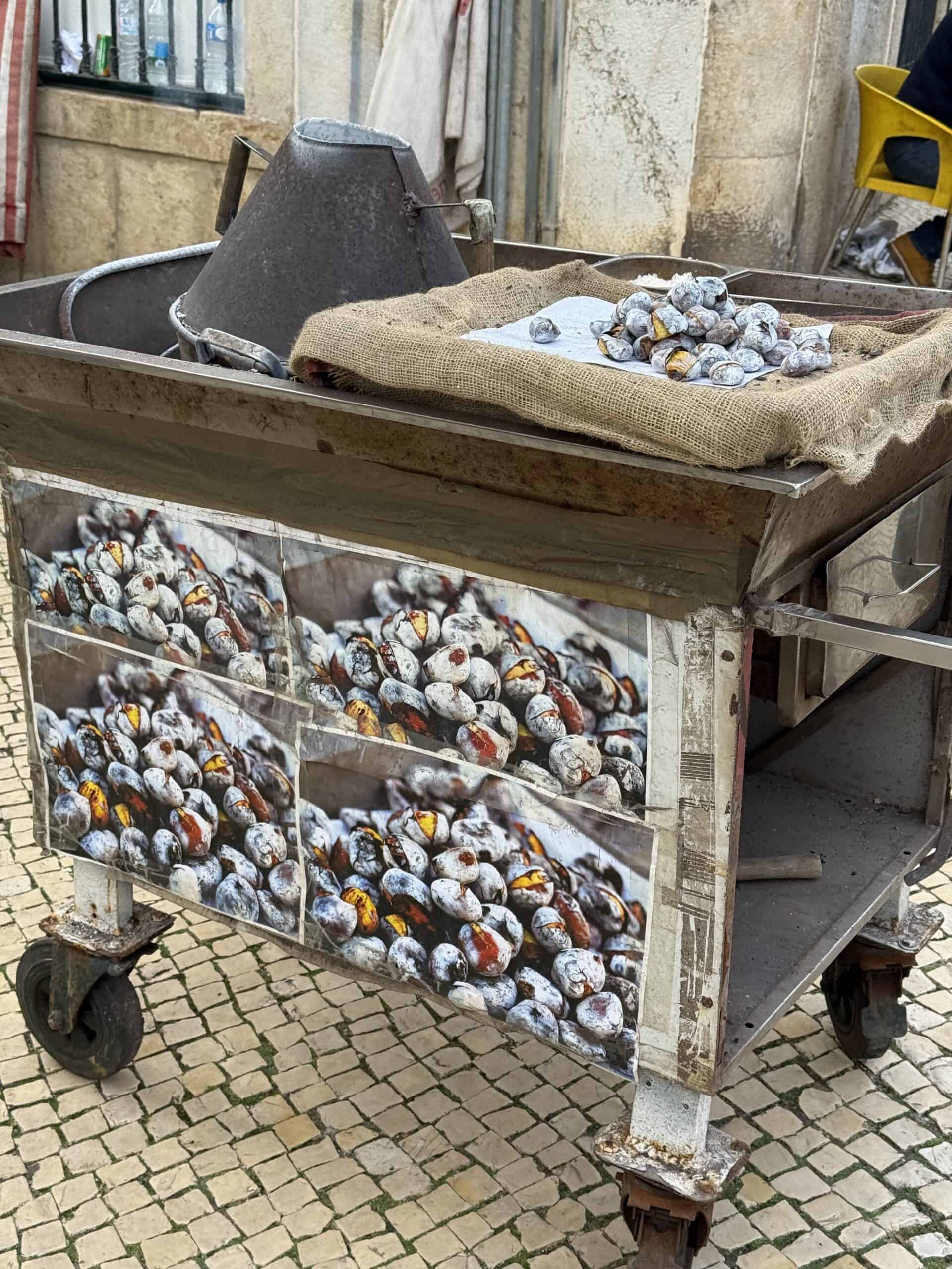Traditional Portuguese castanhas assadas, roasted chestnuts displayed at a street market in Ericeira, Portugal.