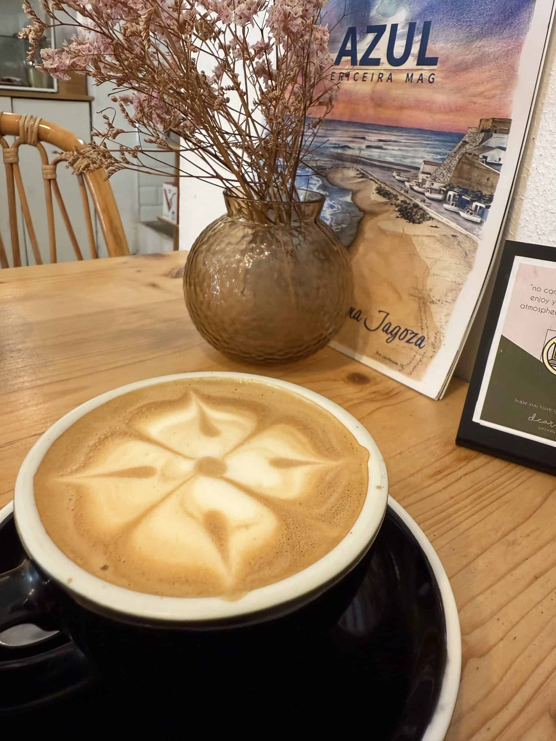 Cappuccino with floral latte art at Dear Rose Café in Ericeira, Portugal.