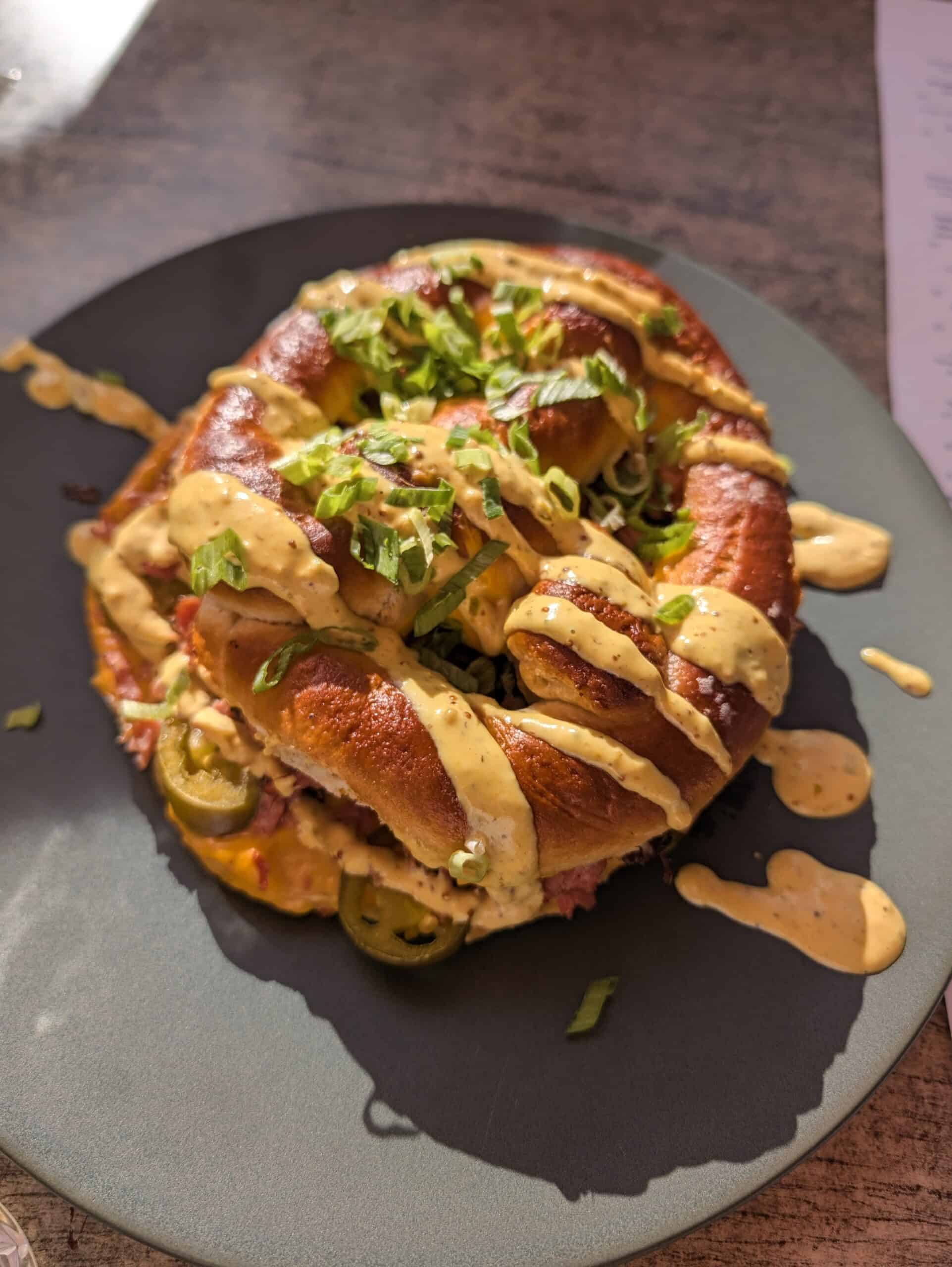 Savory stuffed pretzel topped with creamy sauce and chopped green onions, served at Le Livernois restaurant in Old Quebec City.