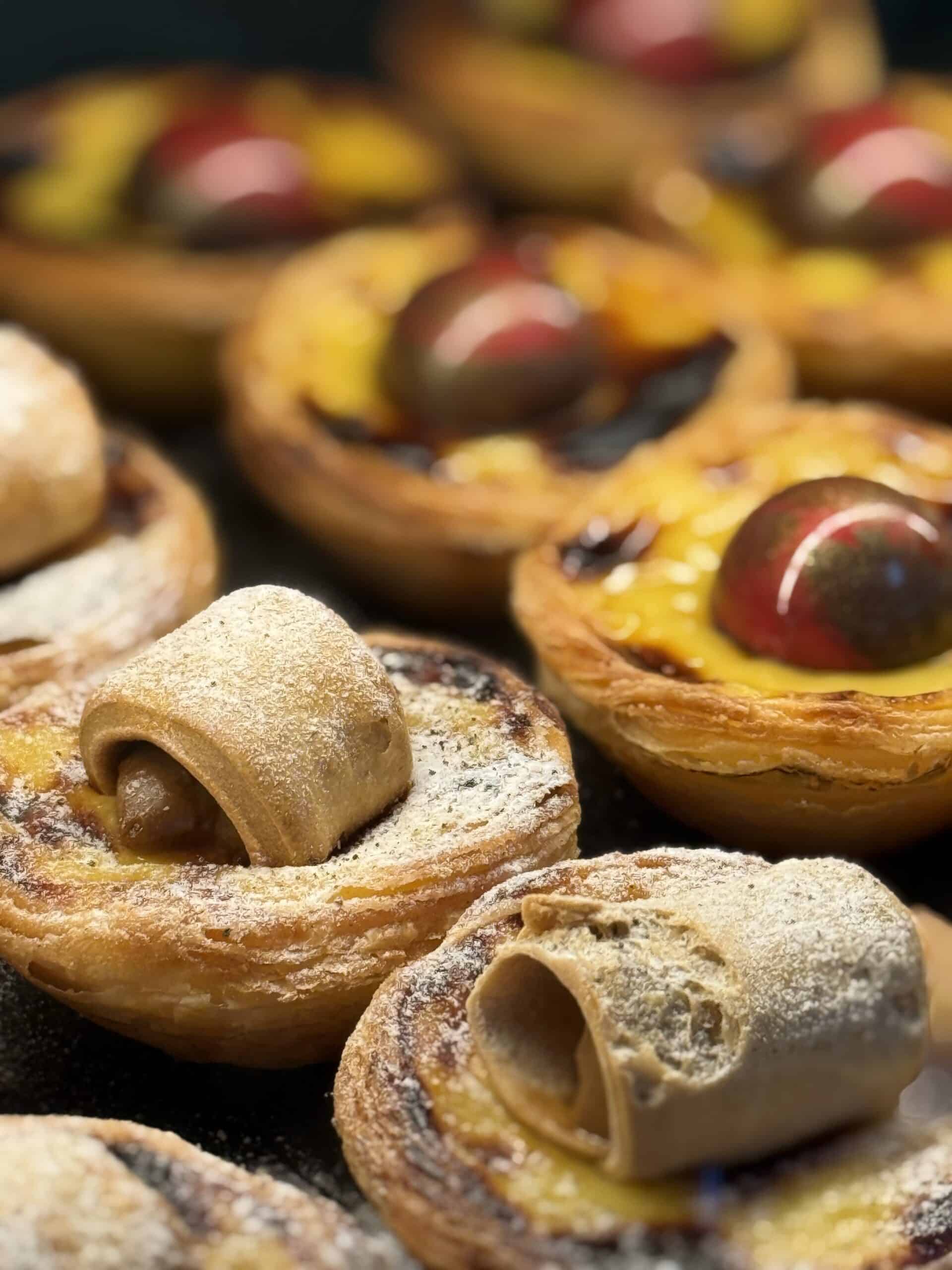 Creative pastel de nata variations with chocolate and pastry toppings displayed at Nat'elier in Lisbon.