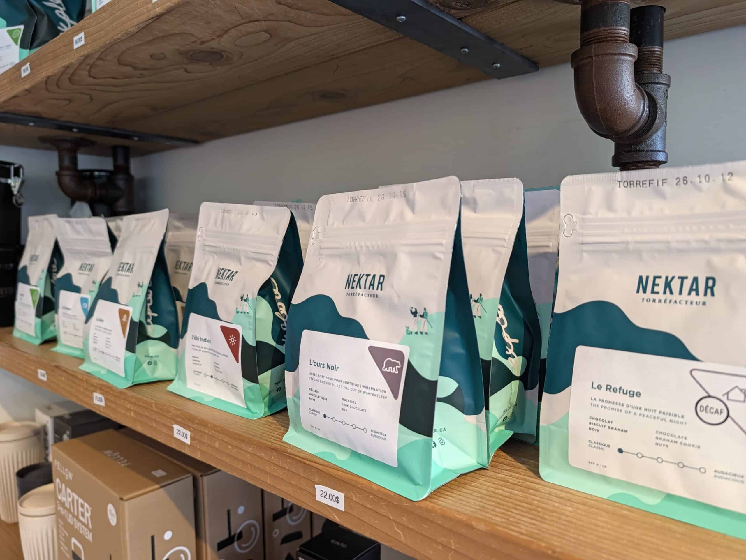 Bags of locally roasted Nektar coffee displayed on wooden shelves at Nektar Caféologue in Limoilou, Quebec City.