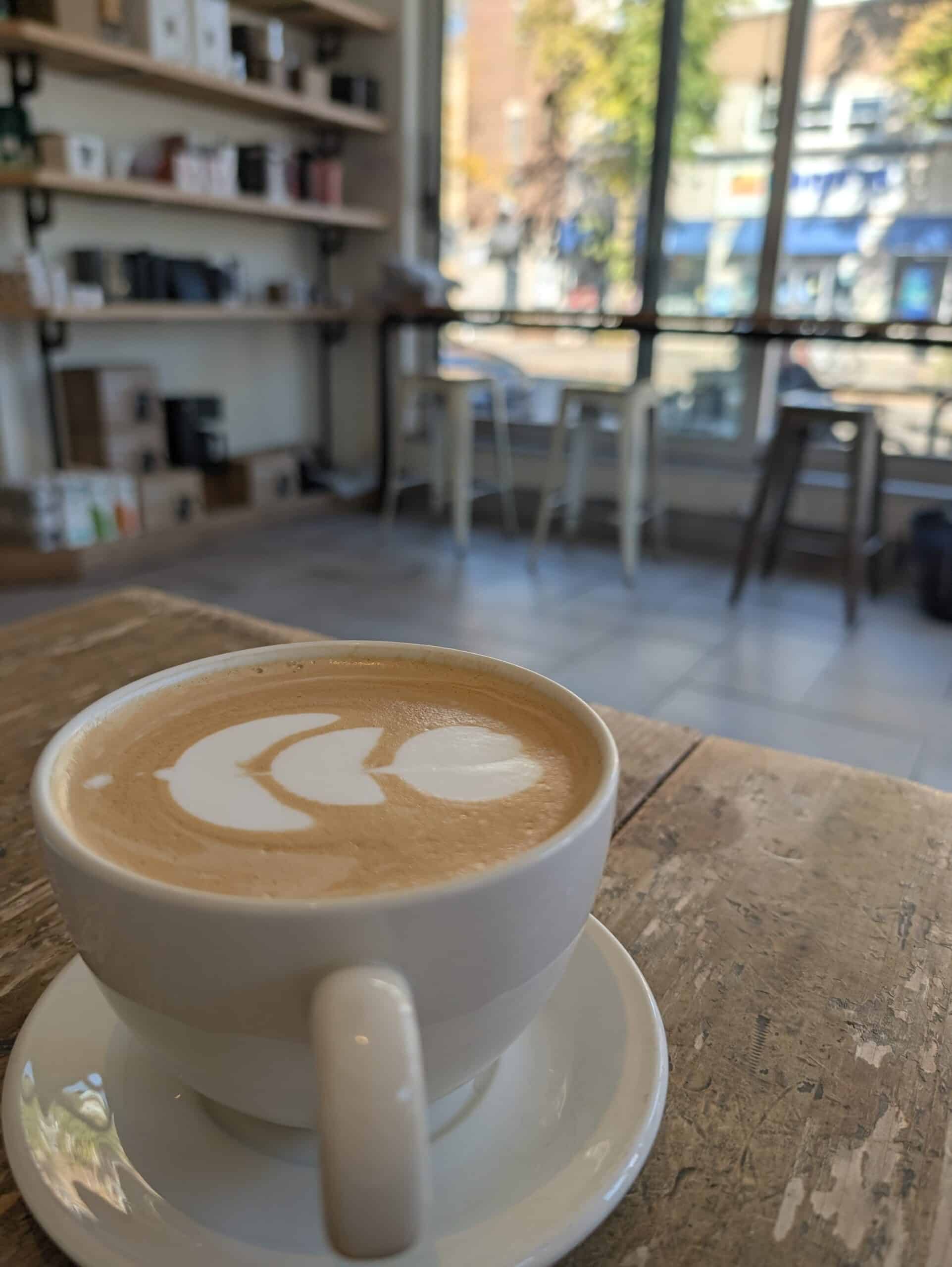 Cup of coffee with heart-shaped latte art on a wooden table at Nektar Caféologue in Quebec City's Limoilou neighbourhood.