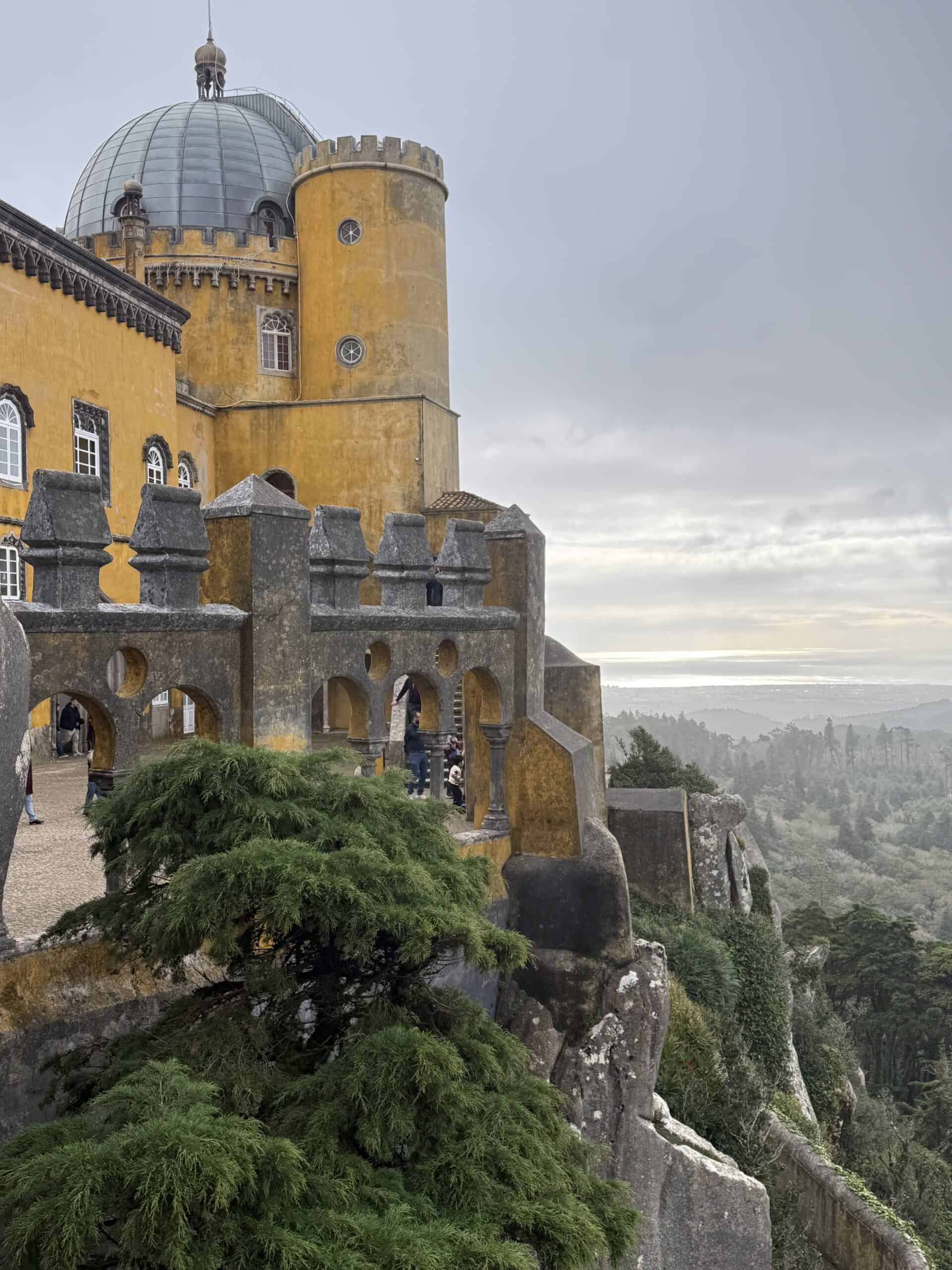 Pena Palace terrace in Sintra overlooking the forested hills beneath a cloudy sky.