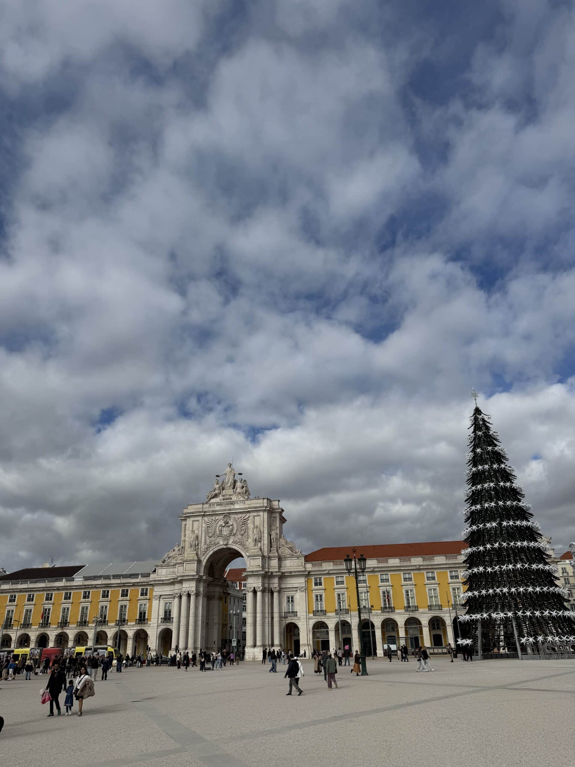 Praça do Comércio in Lisbon decorated for Christmas, with the Rua Augusta Arch, historic yellow buildings and a large Christmas tree.