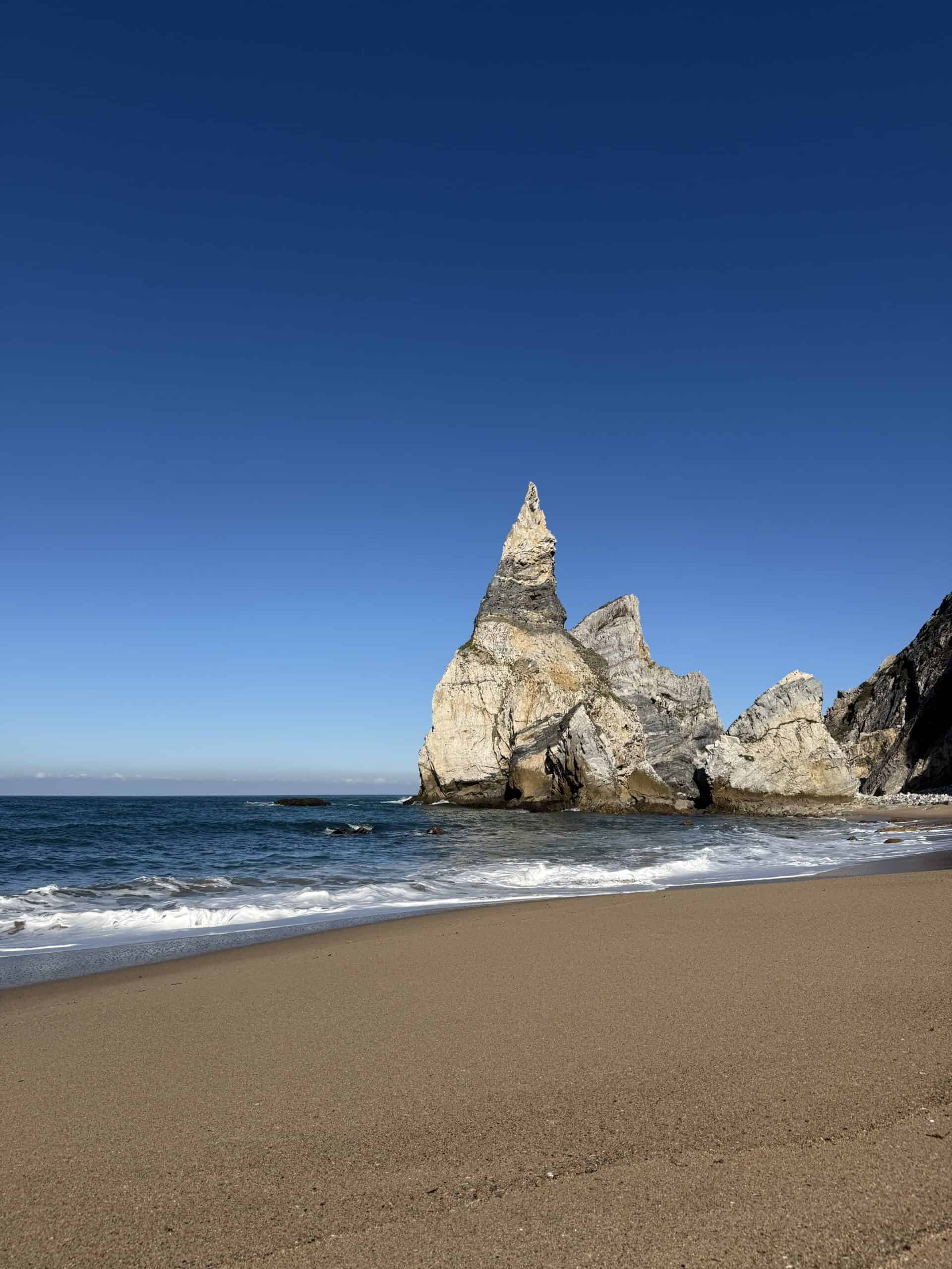 Towering rock formations rising from Praia da Ursa beach beneath the Atlantic cliffs in Portugal