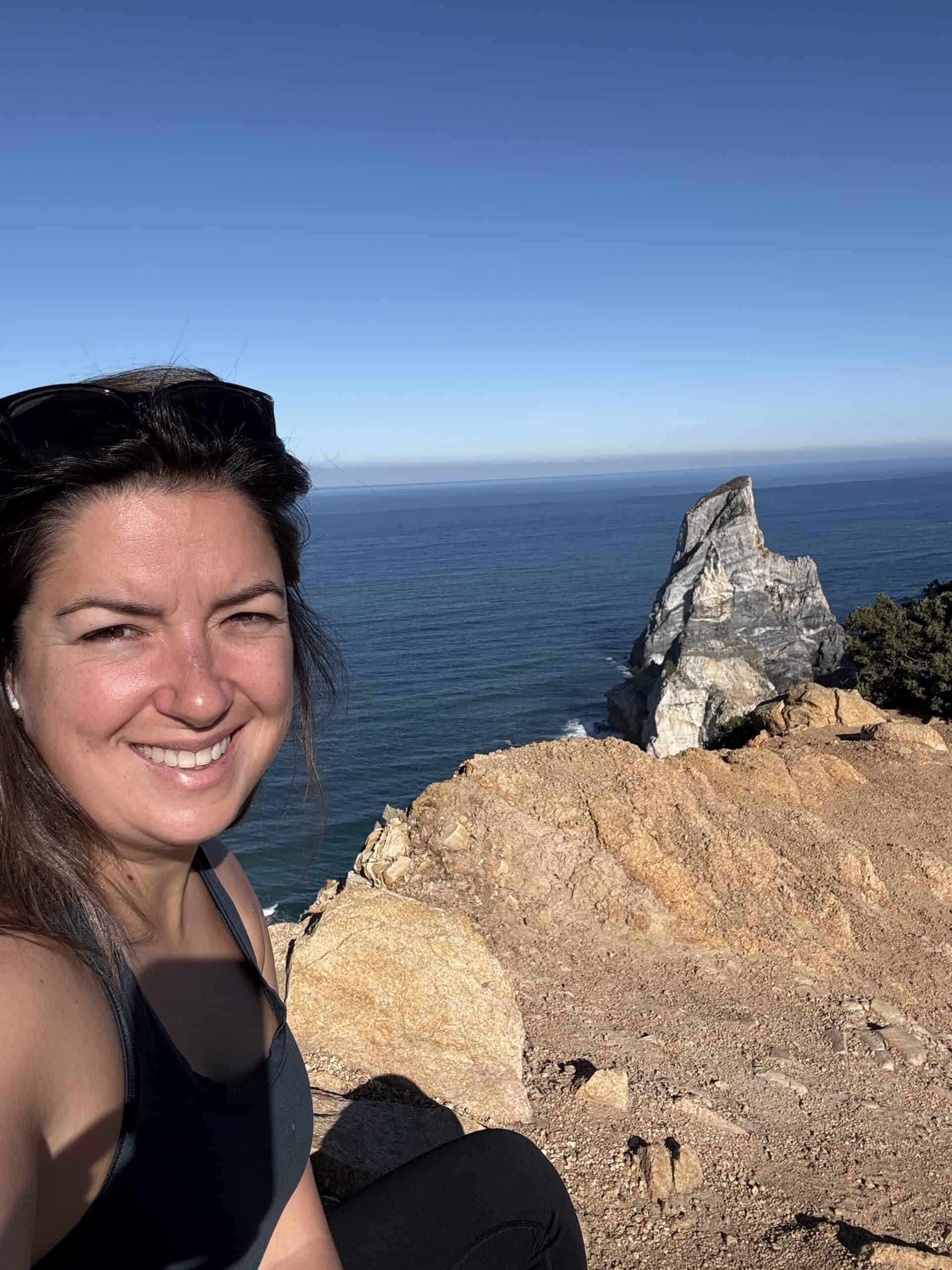 Personal hiking selfie overlooking the rugged Atlantic coastline near Praia da Ursa, Portugal