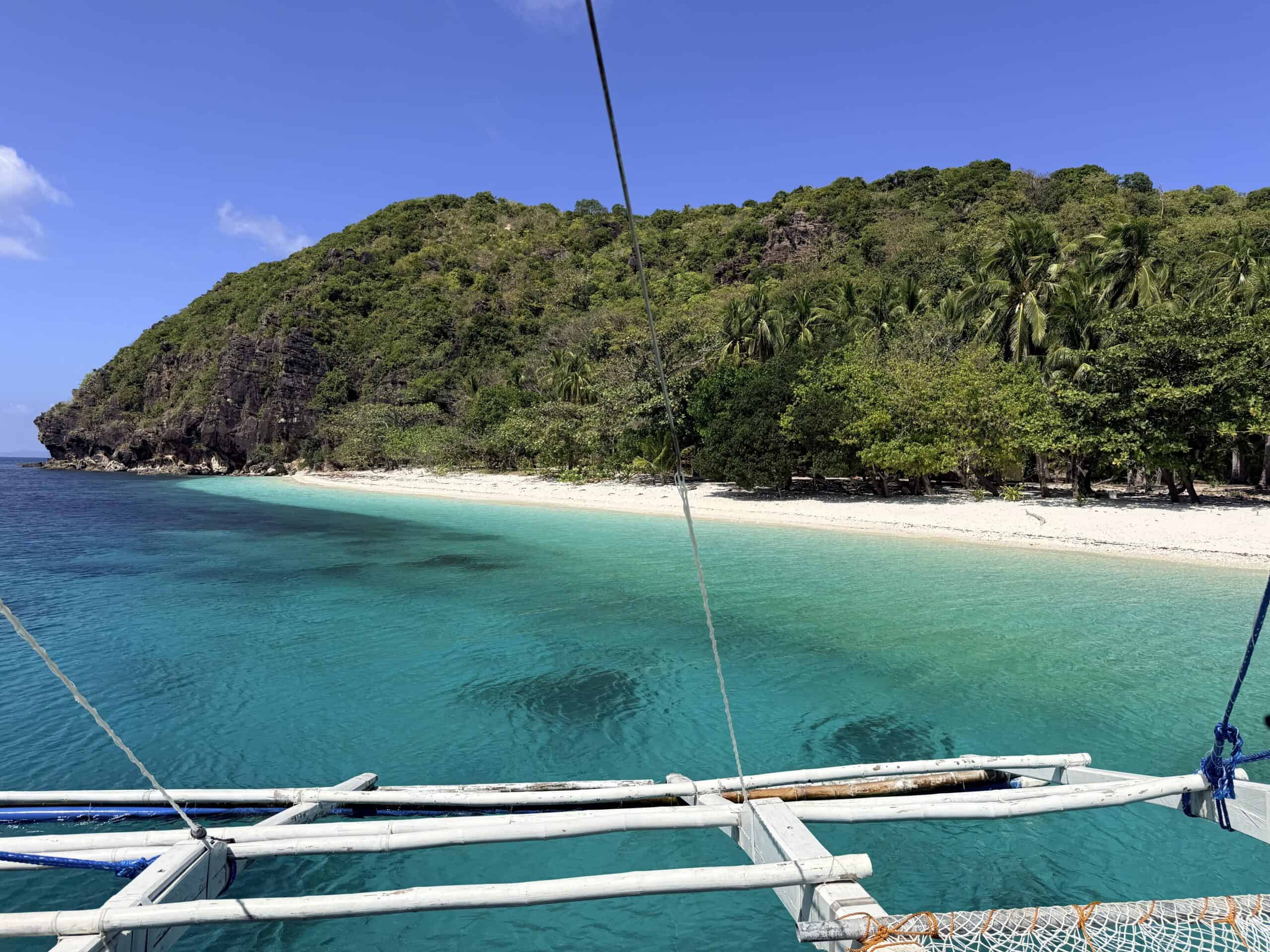 Remote island beach with turquoise water along the El Nido to Coron boat expedition route in Palawan, Philippines