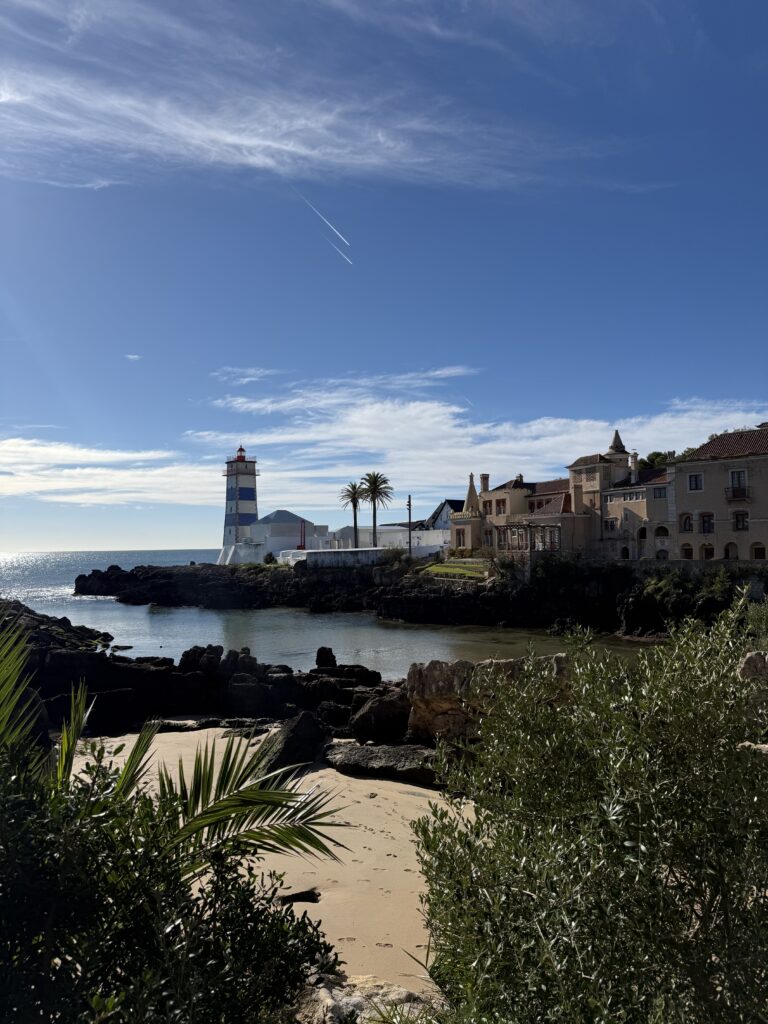 Santa Marta Lighthouse and Casa de Santa Maria overlooking a rocky cove in Cascais, Portugal.
