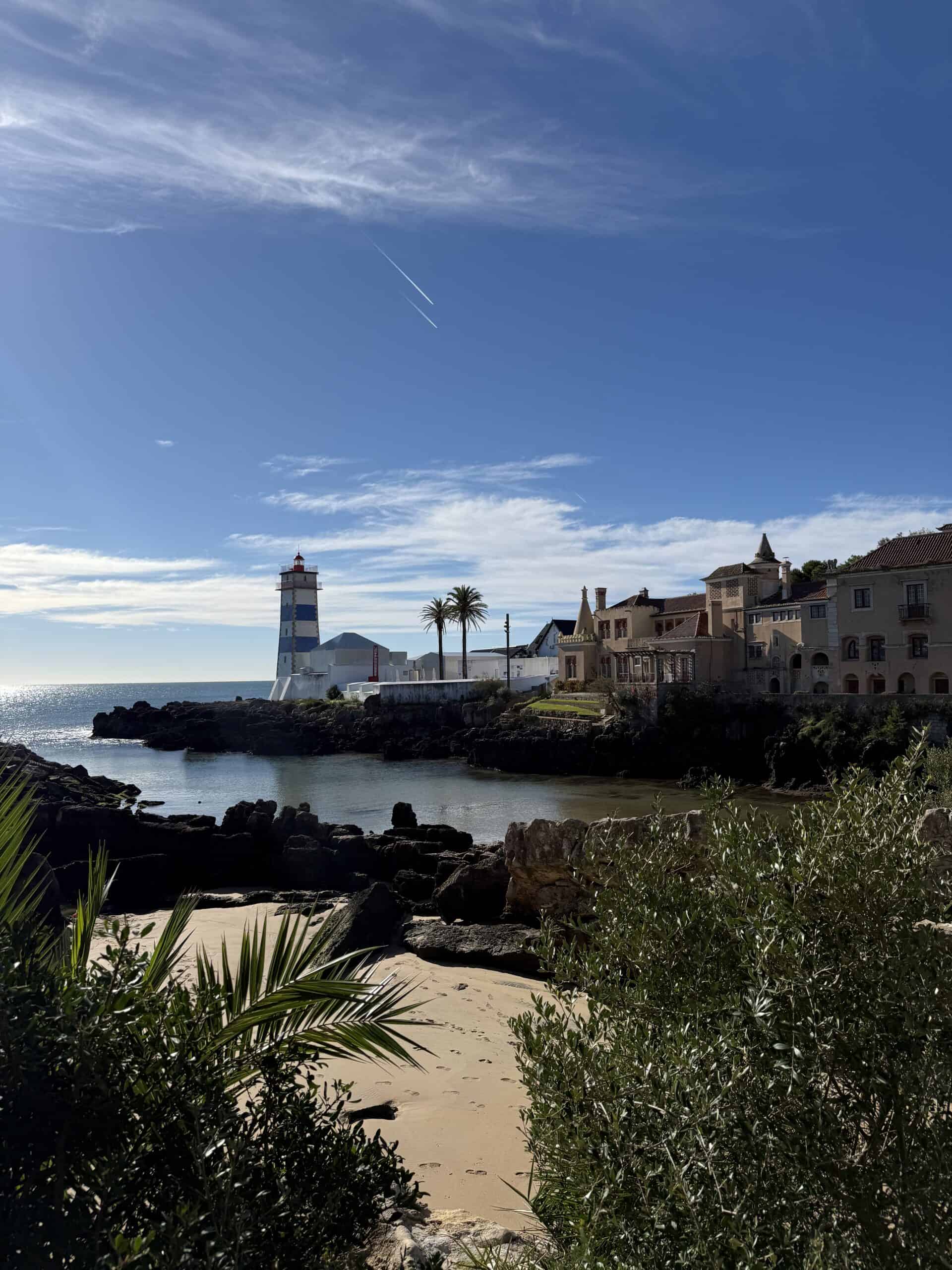 Santa Marta Lighthouse and Casa de Santa Maria overlooking a rocky cove in Cascais, Portugal.
