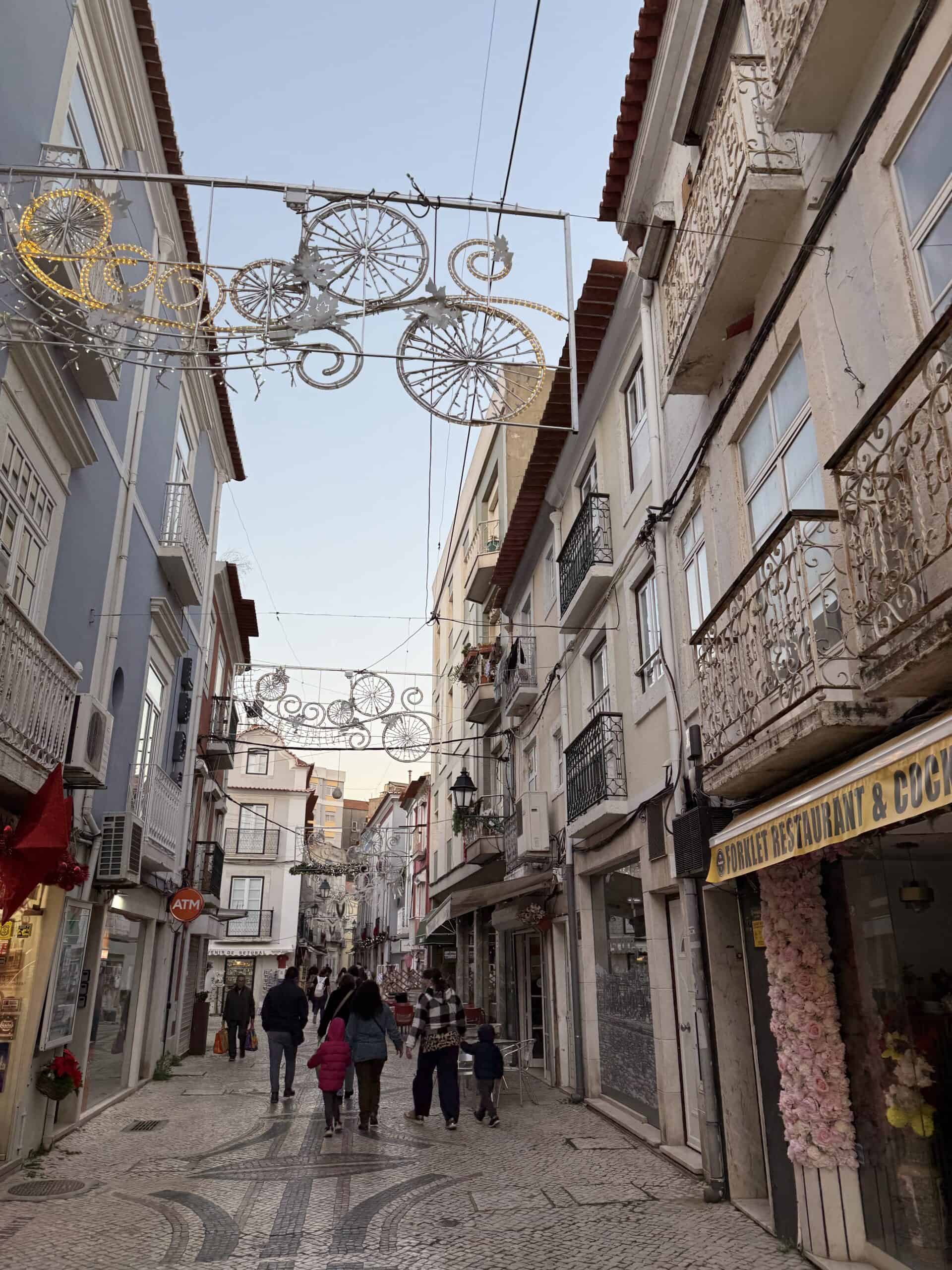 Cobblestone pedestrian street lined with historic buildings, shops and festive decorations in Setúbal, Portugal
