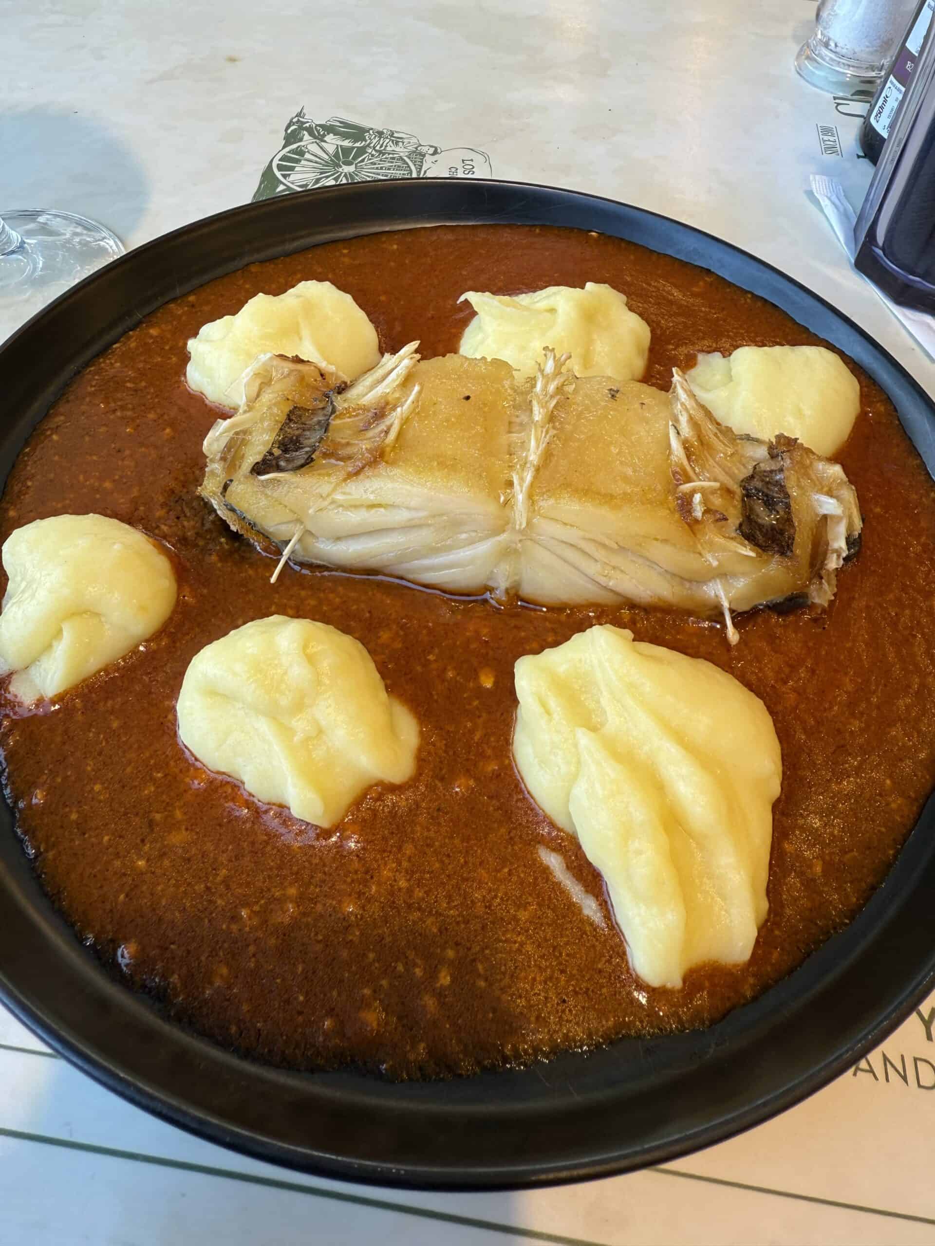 Traditional Portuguese bacalhau codfish served with mashed potatoes and sauce at a restaurant in Lisbon.