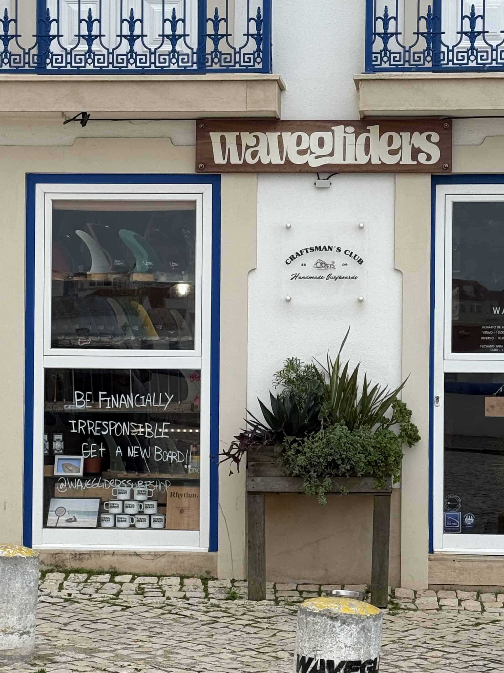 Waveriders surf shop with blue-trimmed windows and surf accessories in Ericeira, Portugal.